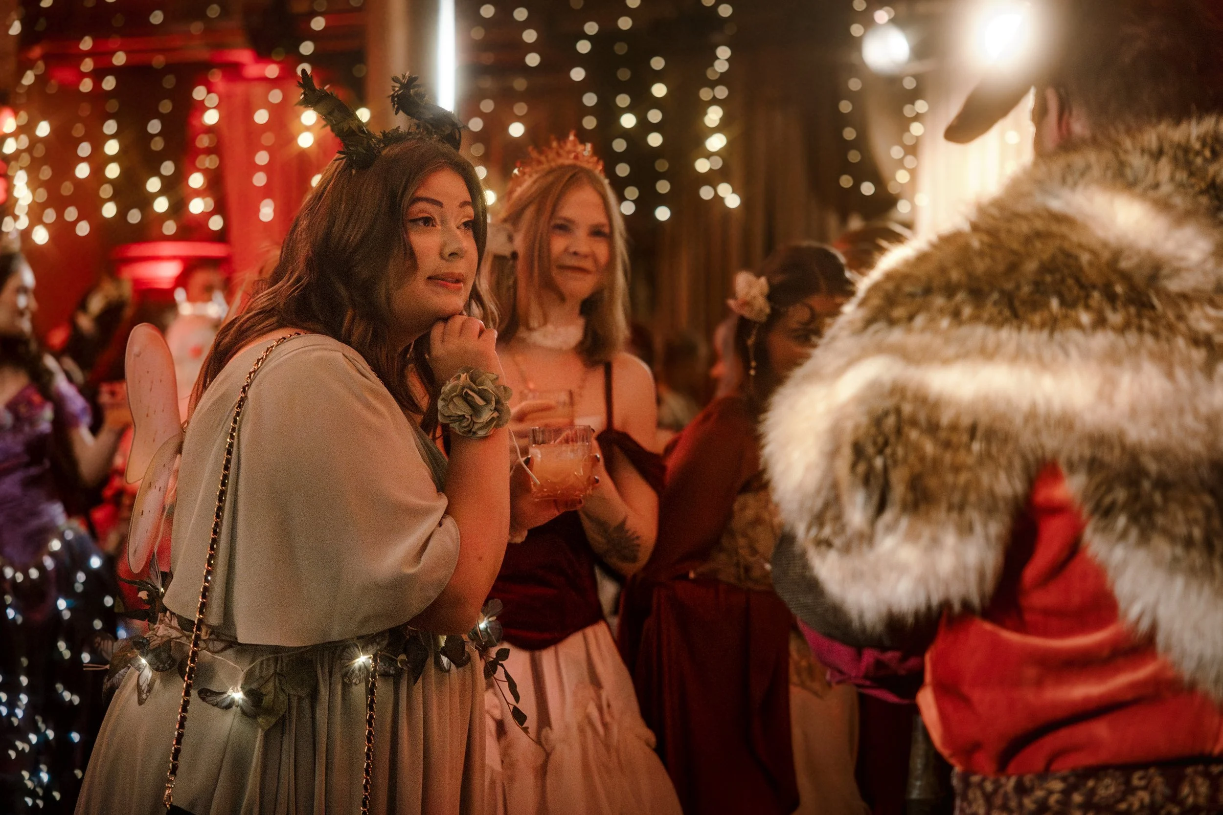 Fantasy dressed women stand in front of the throne havingt an audience with the king and his advisor who are both listening intently