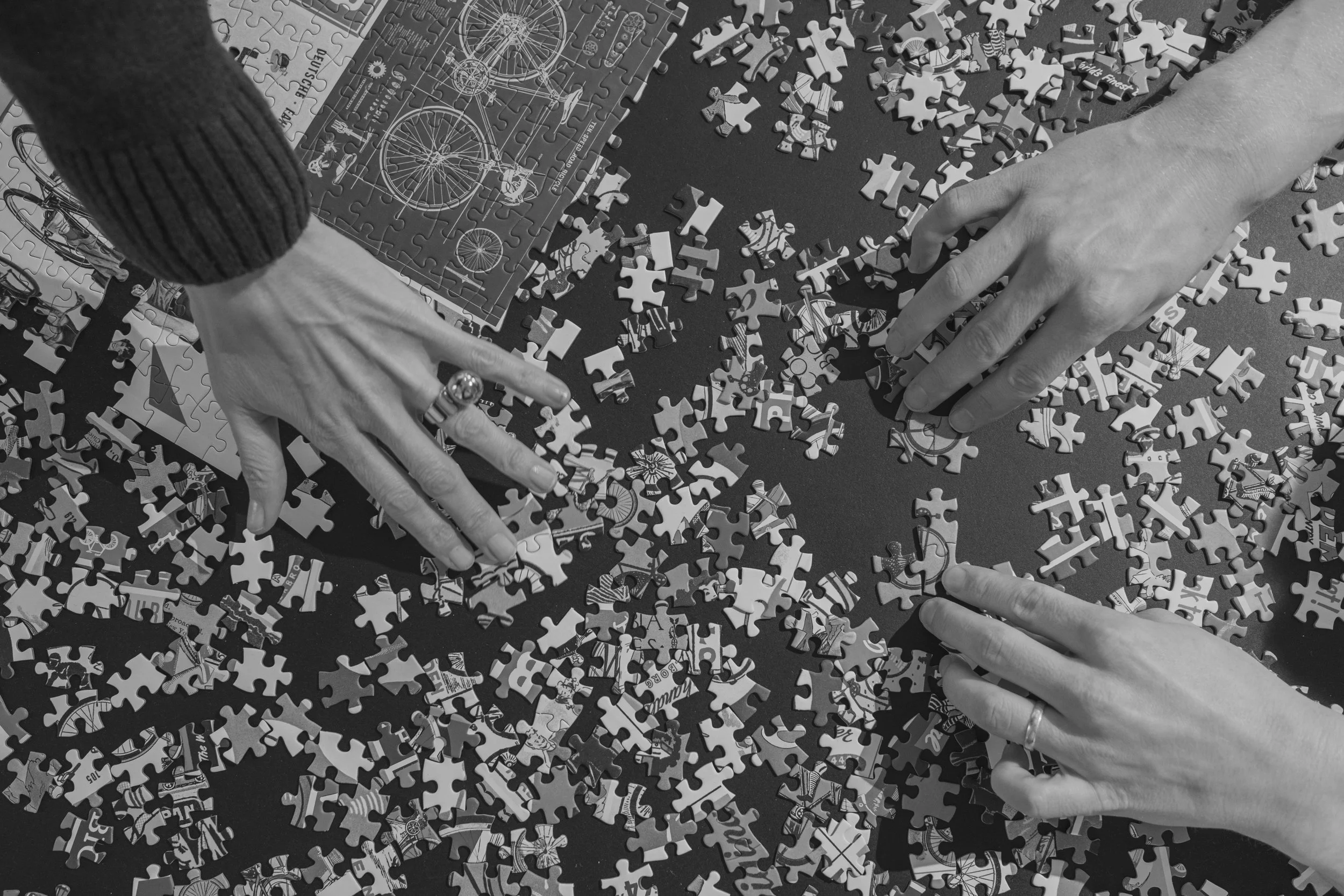 Hands from three people putting together a puzzle