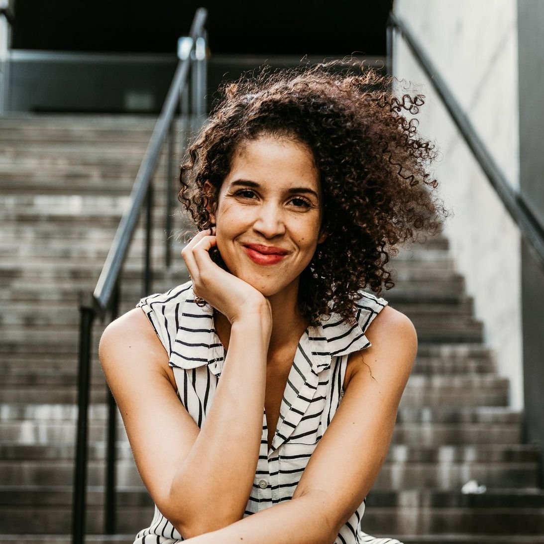 Smiling woman with curly hair sitting on stairs outdoors