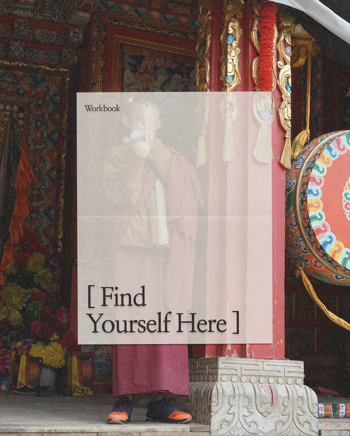 A person in traditional attire standing behind a decorative pink and red structure with colorful ornate decorations and a large colorful circular ornament to the right. The person is partially obscured, with only their legs visible.