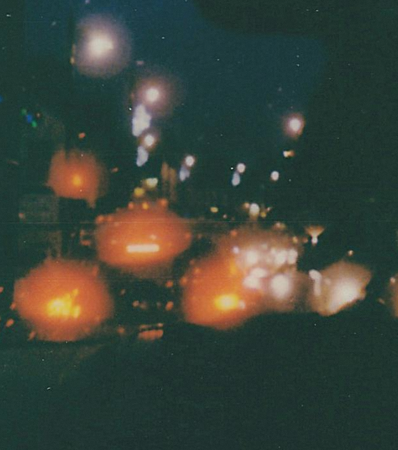 A small house surrounded by dense, colorful forest on a mountainside with cloudy sky overhead.