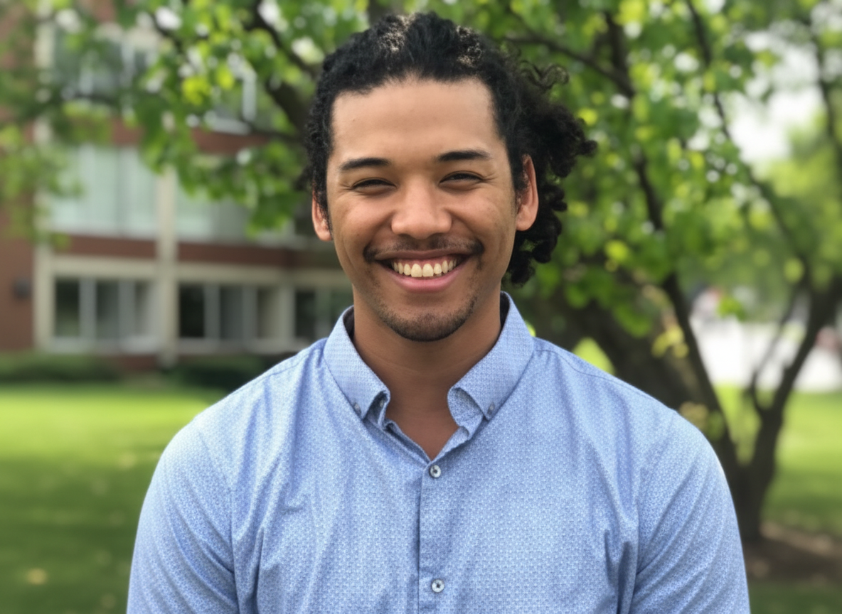 A beige ceramic vase with a narrow neck and wide base, holding a dried branch with small round seed pods, placed on a wooden surface against a plain wall.