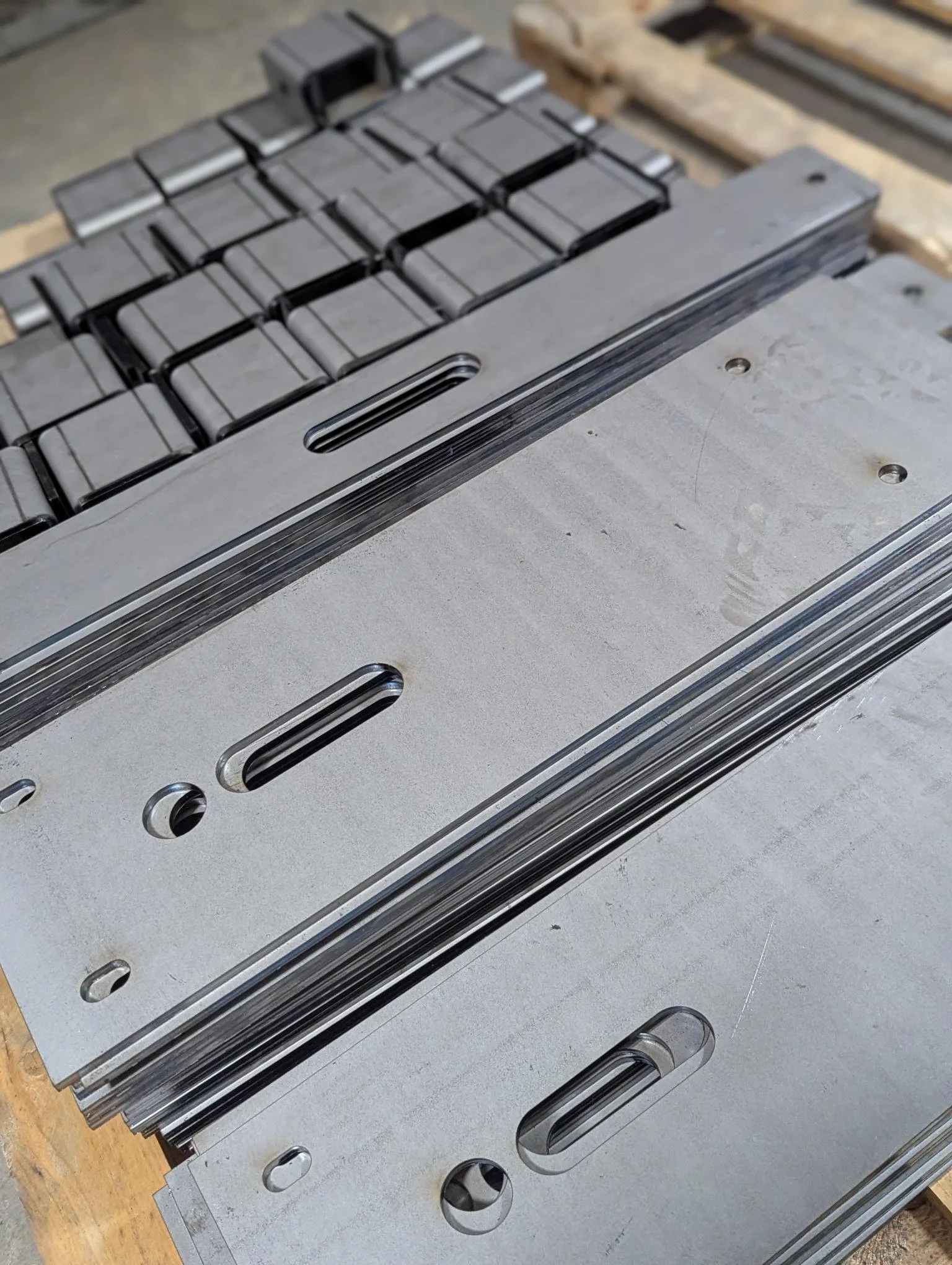 Metal machined parts with slots and holes on a wooden surface
