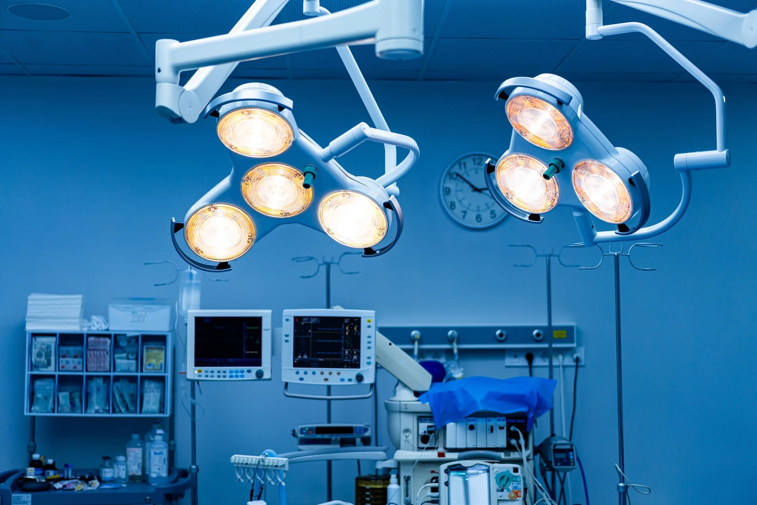 An operating room with bright surgical lights, medical monitors, and surgical equipment, all set up for a procedure.