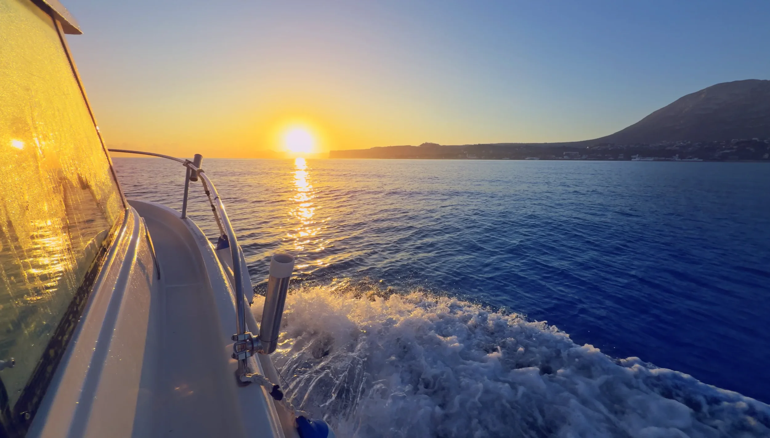 Sunset boat trip from Denia with wake and low sun over the sea