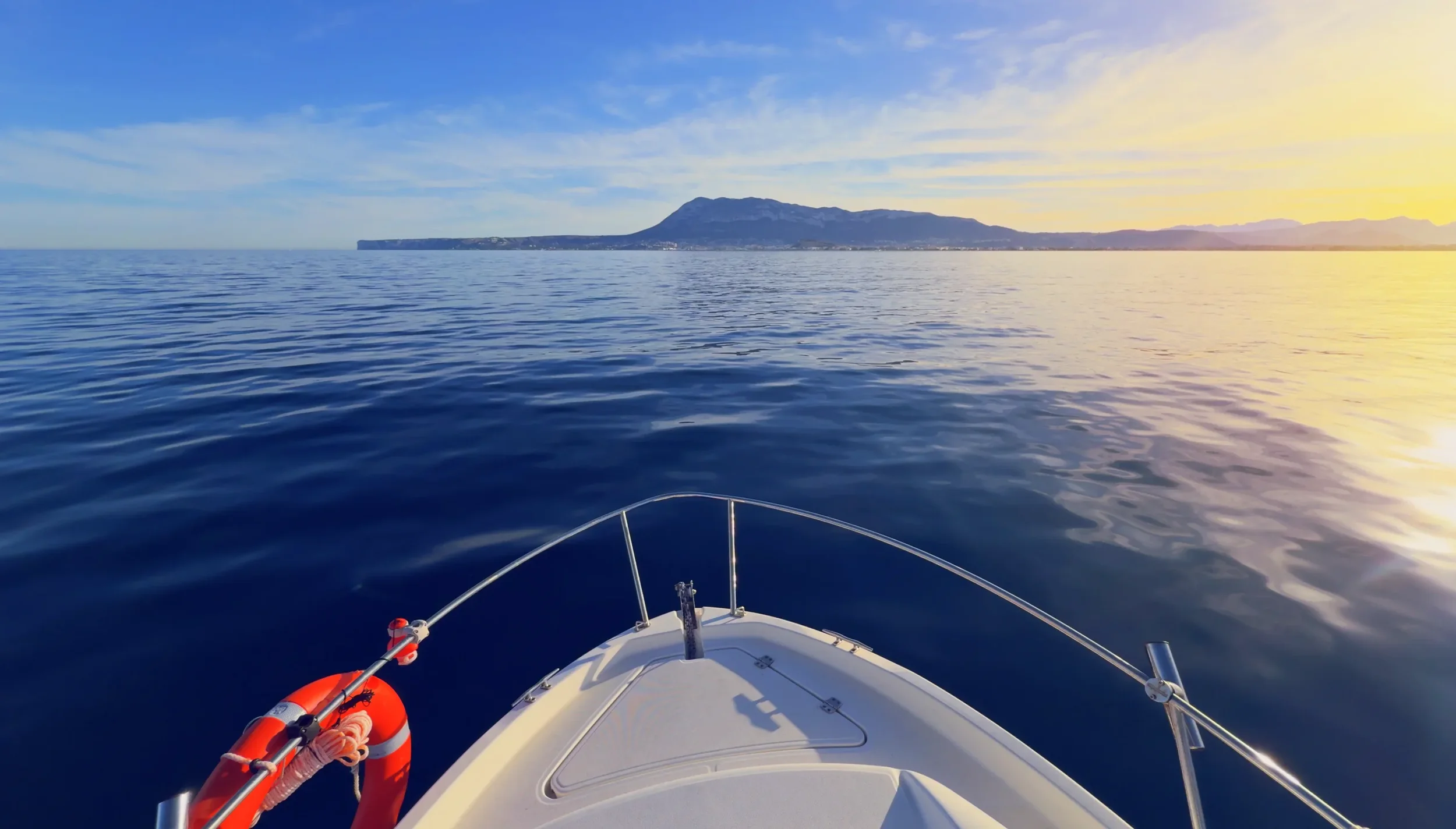 Boat bow cruising at sunset on a calm sea in Denia