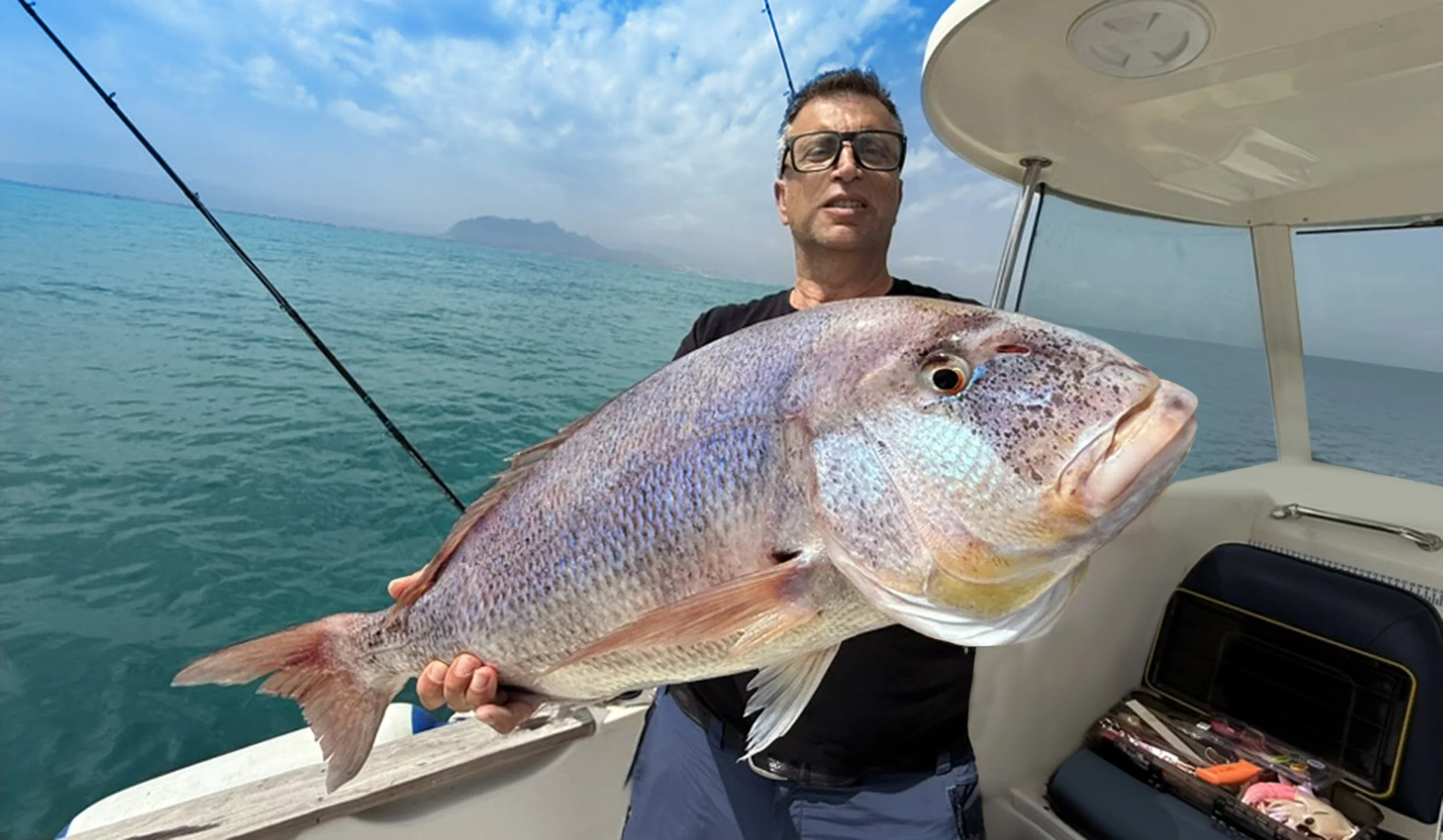 Angler Man holding a freshly caught dentex on a Denia fishing charter boat
