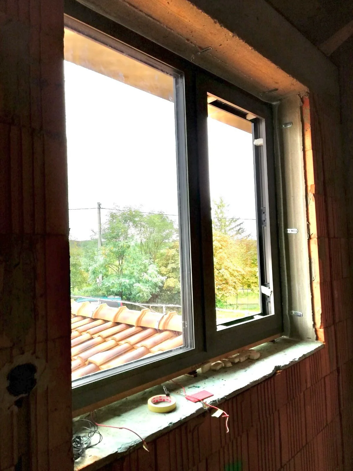 This is the installation of a heating window in a family house near Bratislava. It is shown during construction, with exposed brickwork and a partially finished interior.