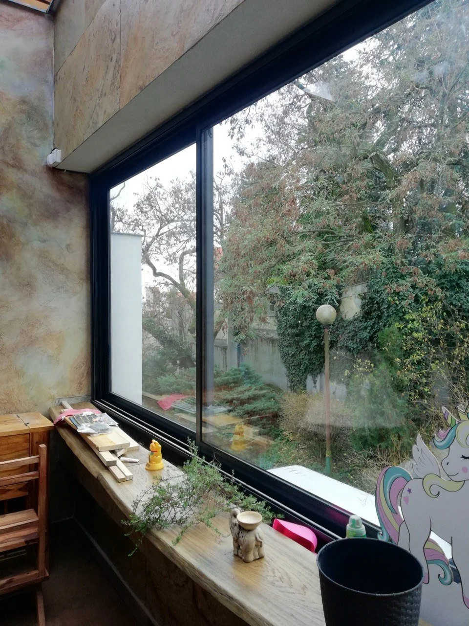 Loggia area of a residential apartment in Bratislava, featuring a large window with a view of the garden and interior decorative elements.