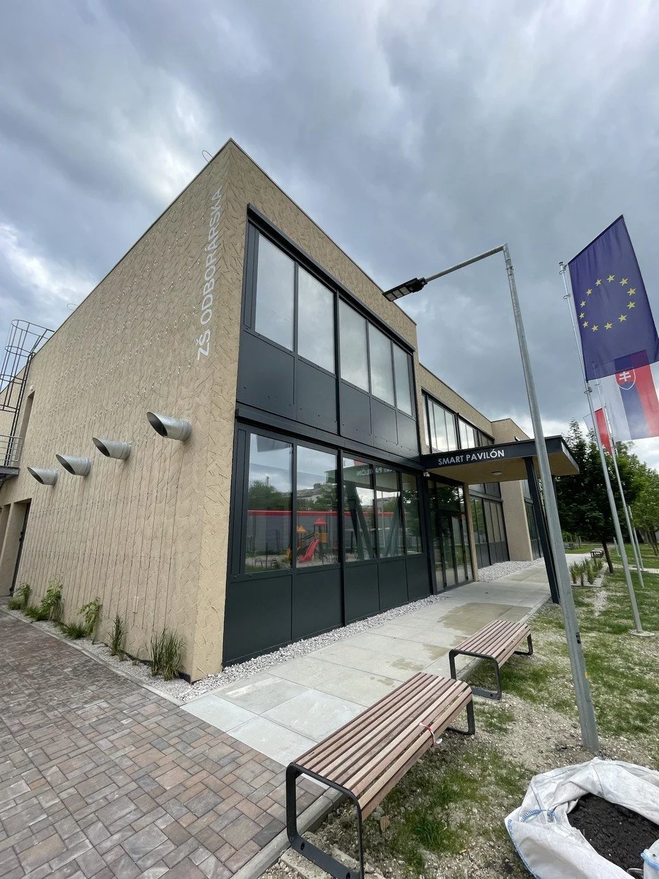 This is a modern elementary school building known as ZŠ Odborárska, featuring a Smart Pavilion entrance and large-format glazing. The building is part of a project funded by the European Union