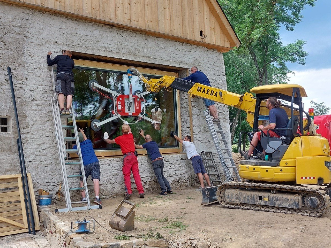 Installation of a large heating glass panel on a historic building near Bratislava, using a vacuum lifting system and a team of workers during construction