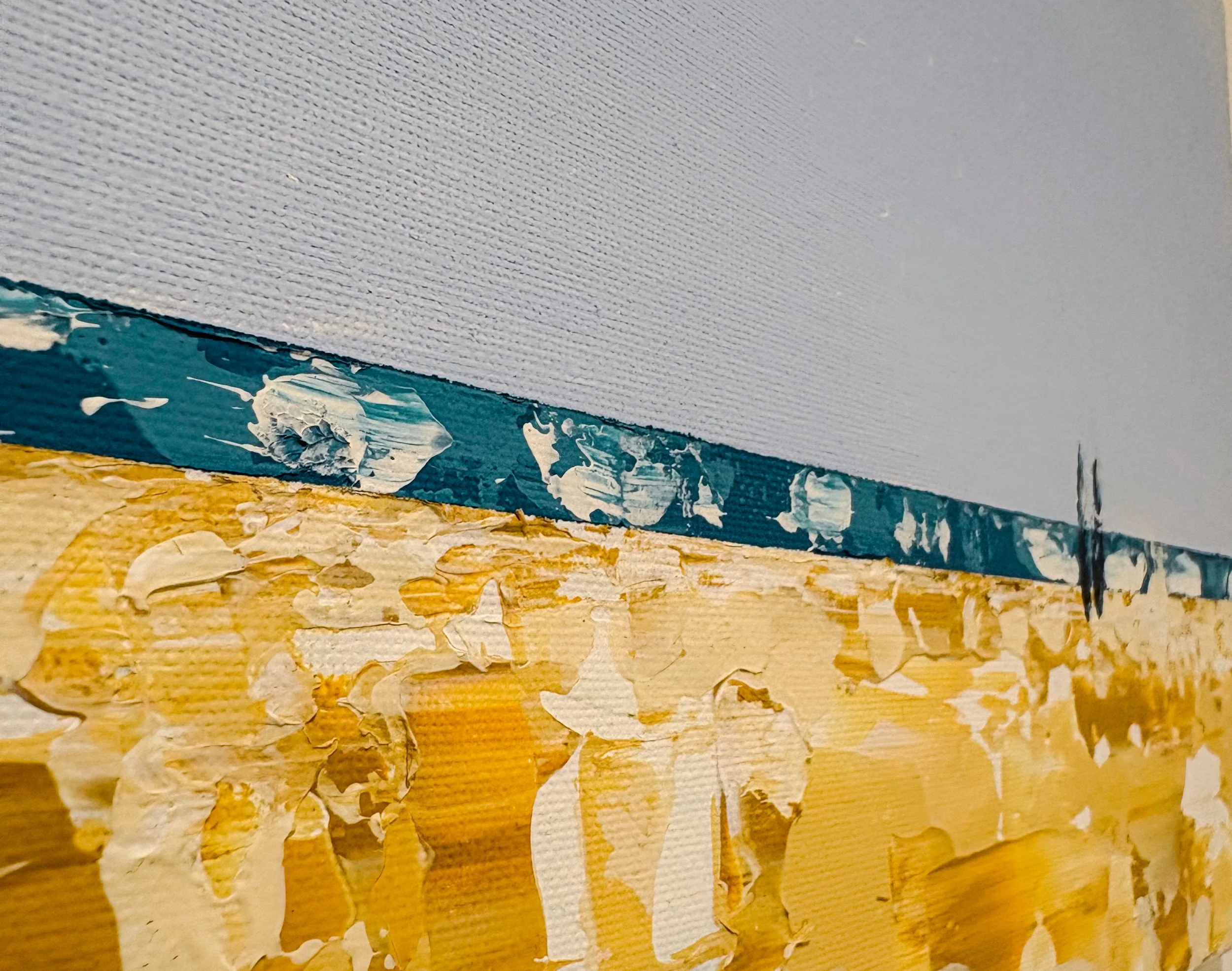 Close-up of a canvas with textured impasto painting, secured edges and angled view of abstract art in blue, white, and sand like yellows on a canvas surface.