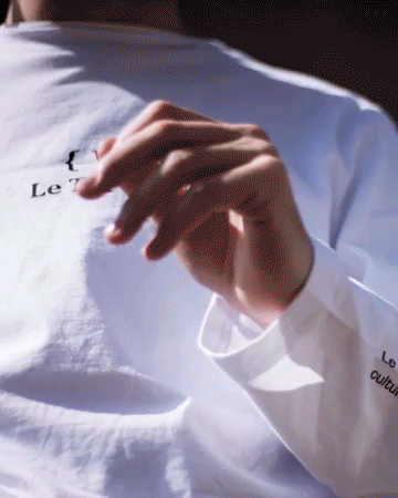 Une personne tenant un crayon ou un stylo, vêtue d'une chemise blanche.