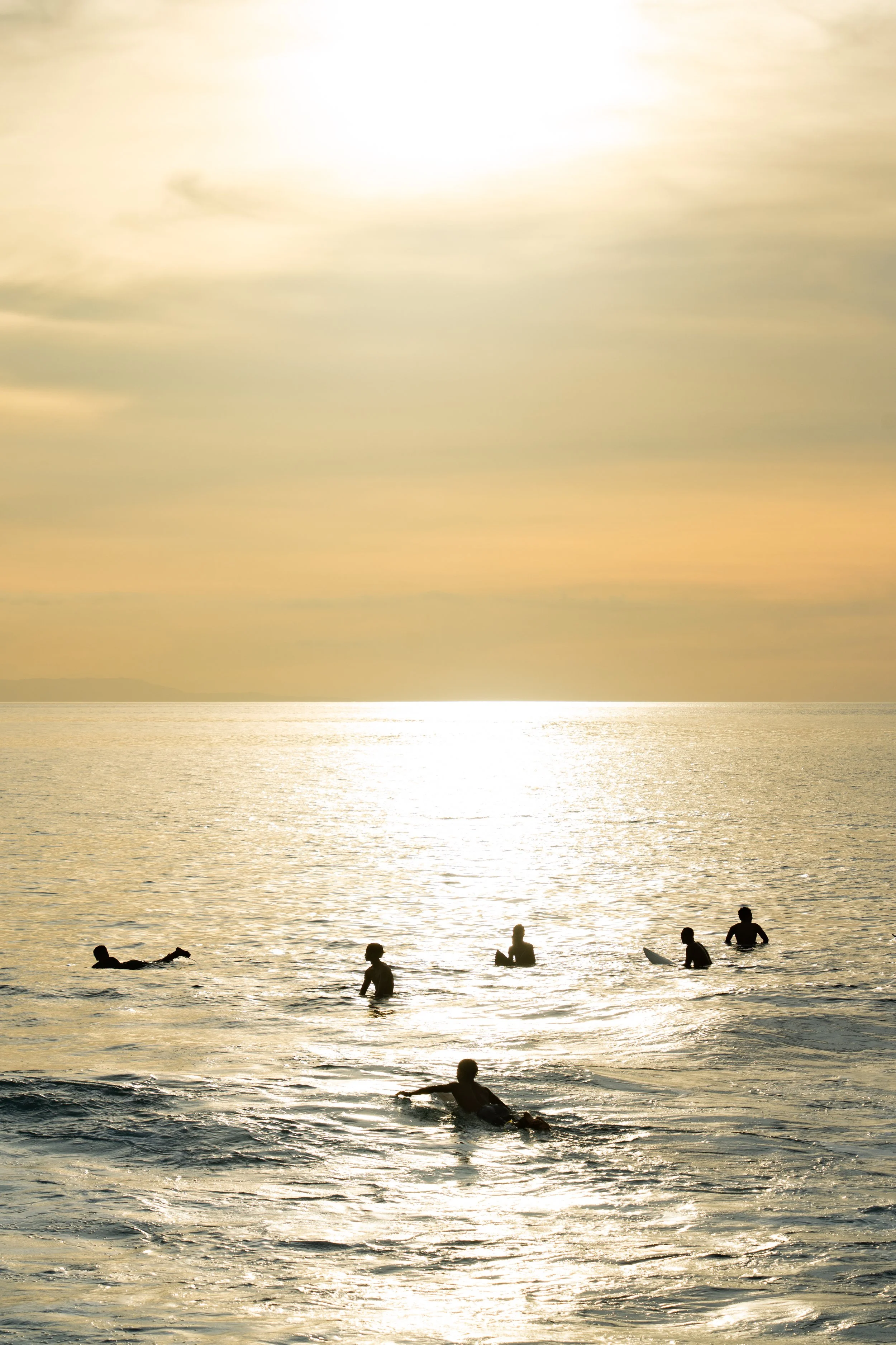 Gezicht op de zee met mensen die zwemmen en spelen in het water tijdens zonsondergang