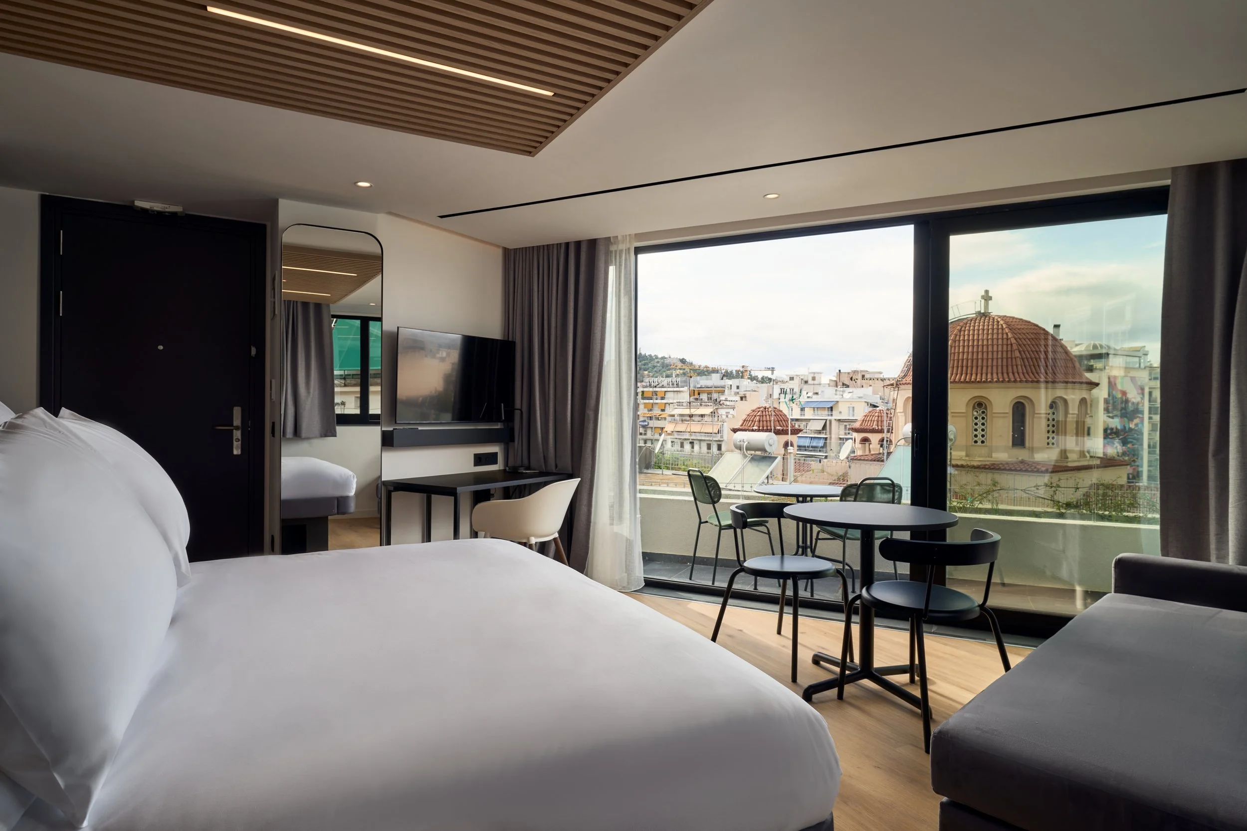 Double bed, desk and balcony with city view