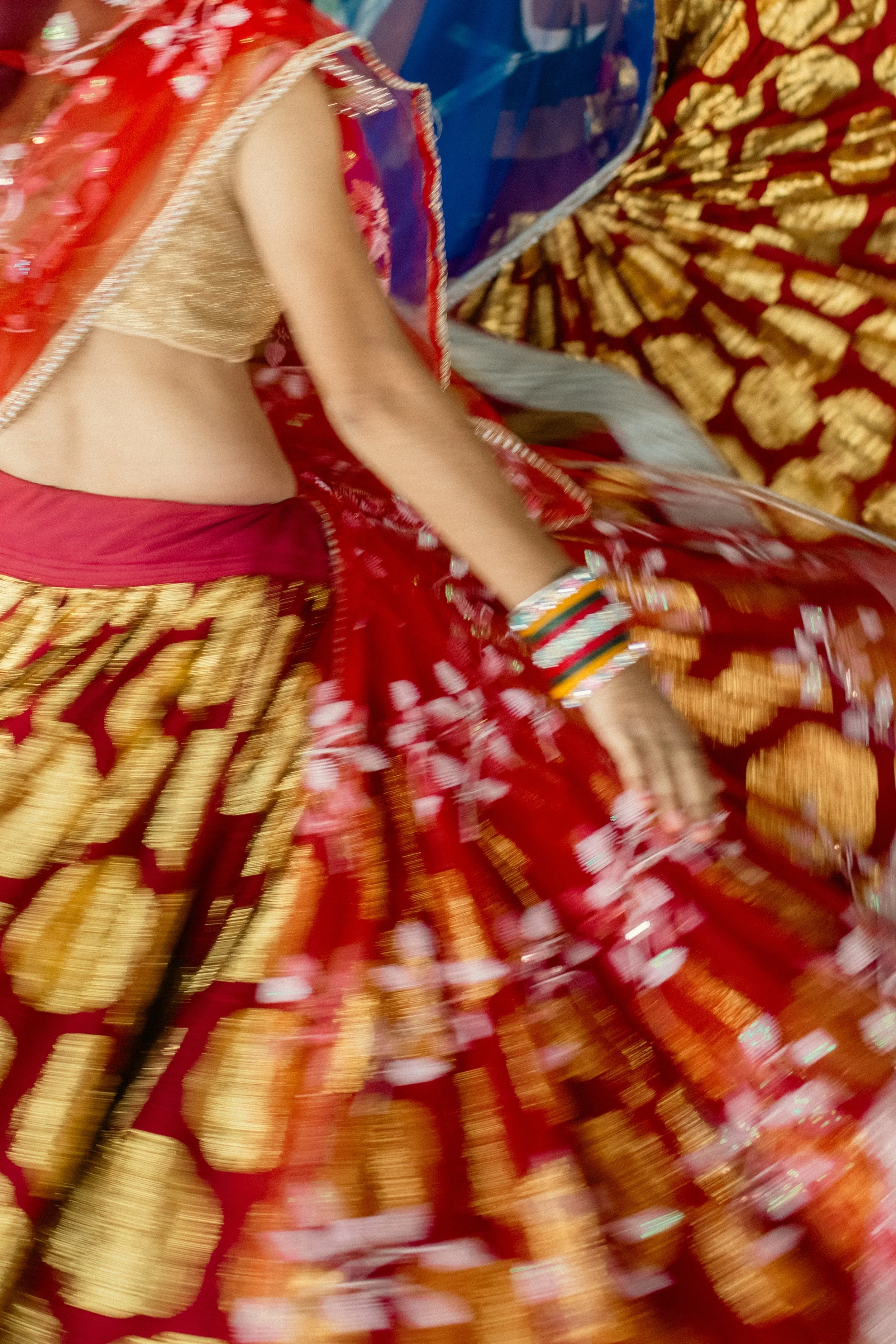 A person wearing a traditional red and gold Indian outfit with intricate patterns and embellishments, possibly a wedding or festive attire.