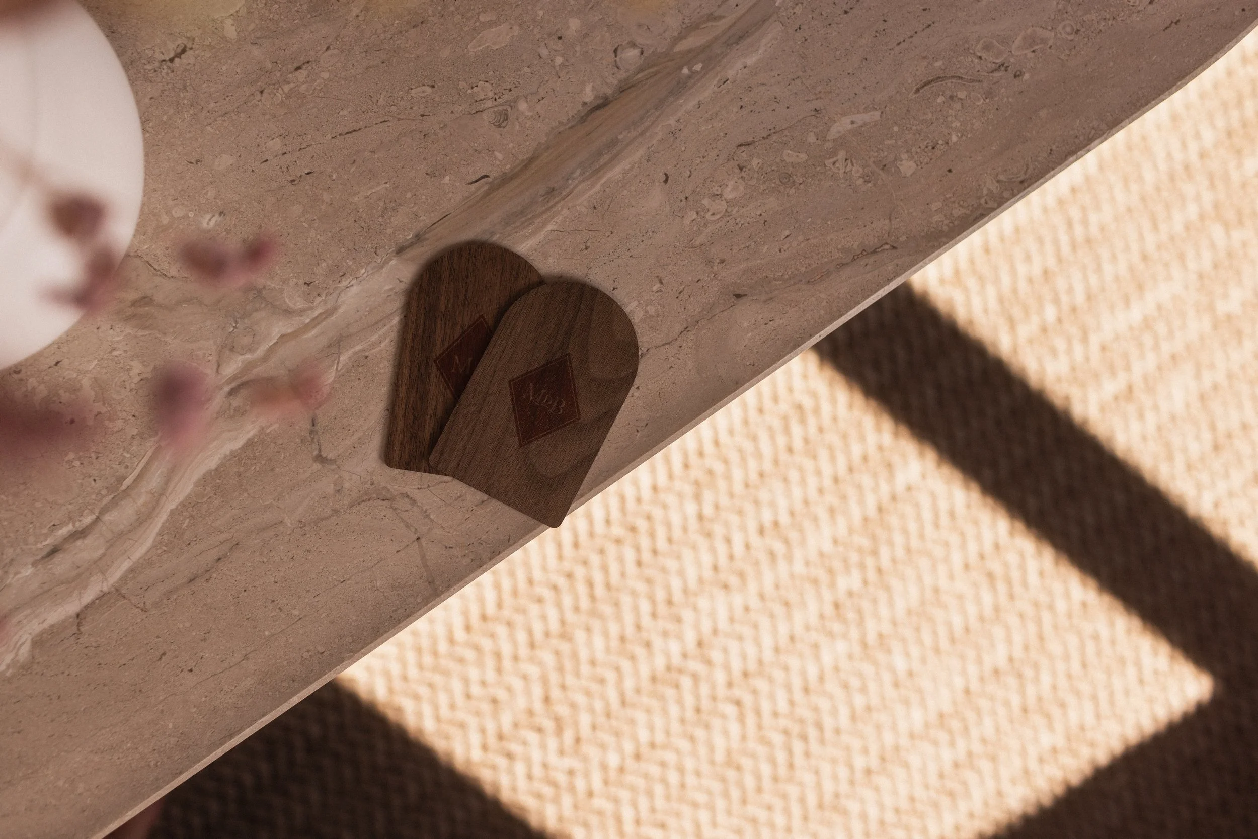 Close-up of a marble countertop with a wooden heart-shaped object and flowers at Mas d'en Bruno. Interior detail photography by Valerie.