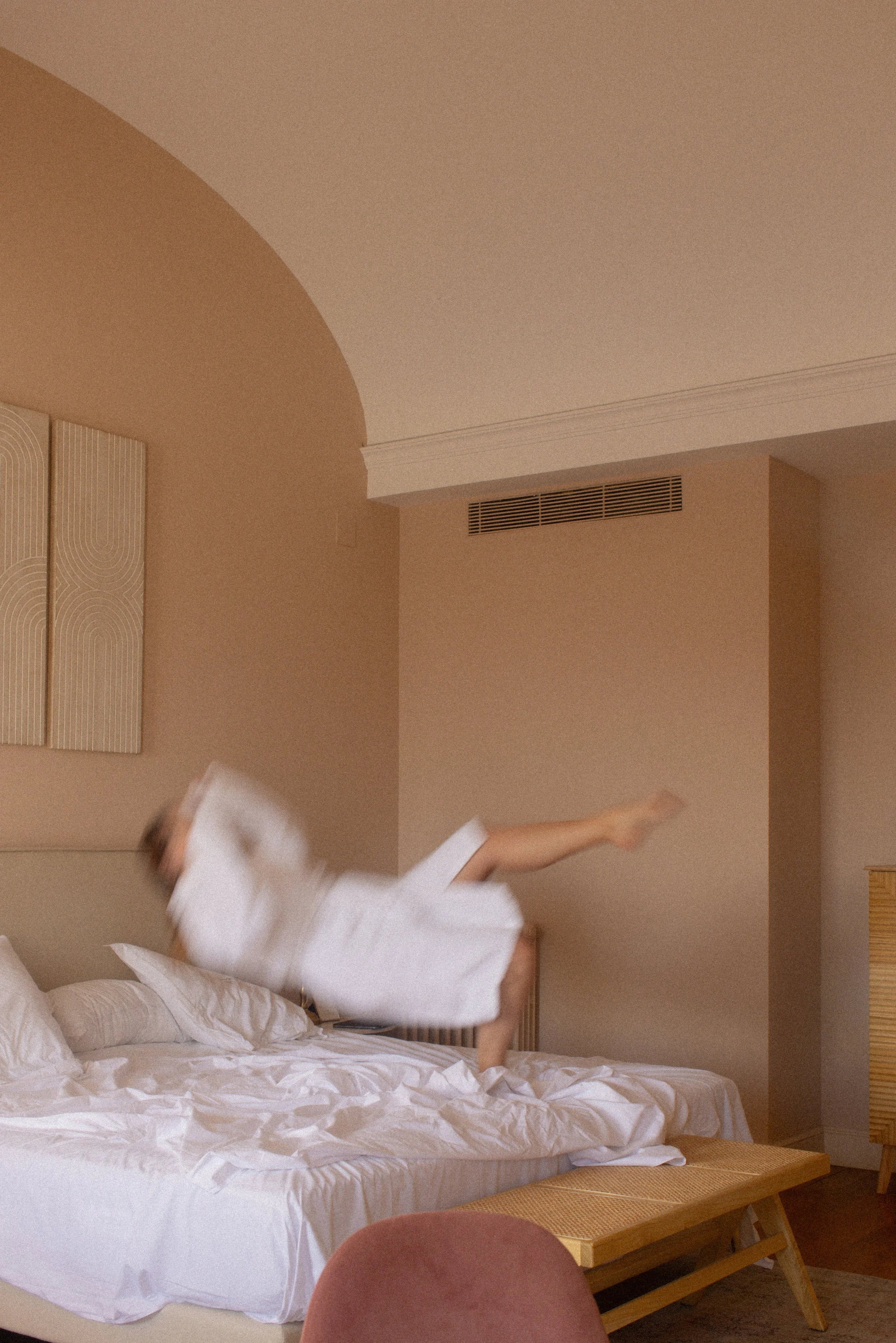 Person falling onto a bed in a boutique hotel room at Font de la Canya, Catalonia, Spain.