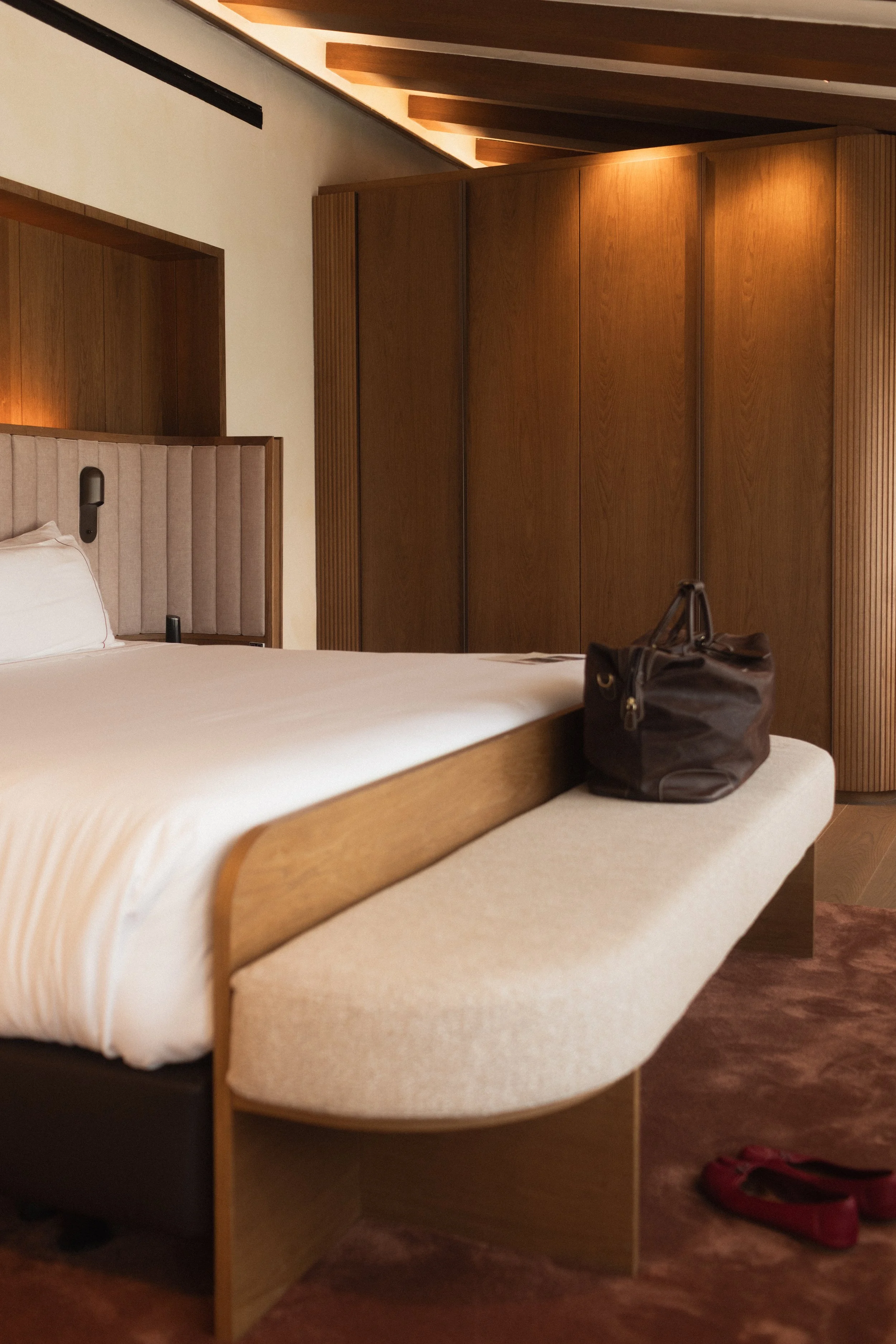 Refined suite arrival at Mas d'en Bruno: a glimpse into the luxury guest quarters featuring a classic wooden wardrobe and welcoming red slippers in Priorat.