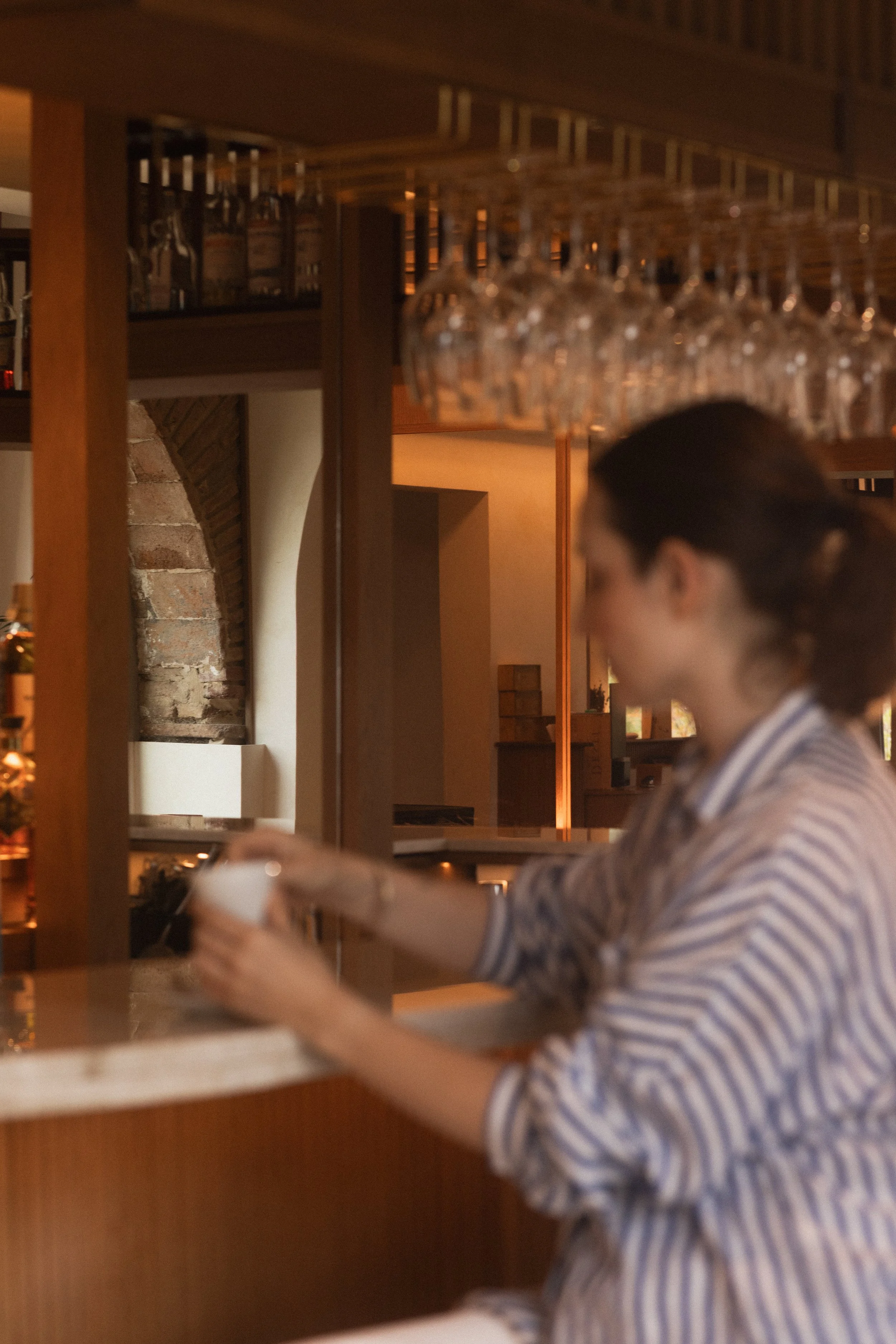 Intimate bar atmosphere at Mas d'en Bruno: a guest enjoying a quiet coffee moment at the elegant bar counter in the heart of Priorat.