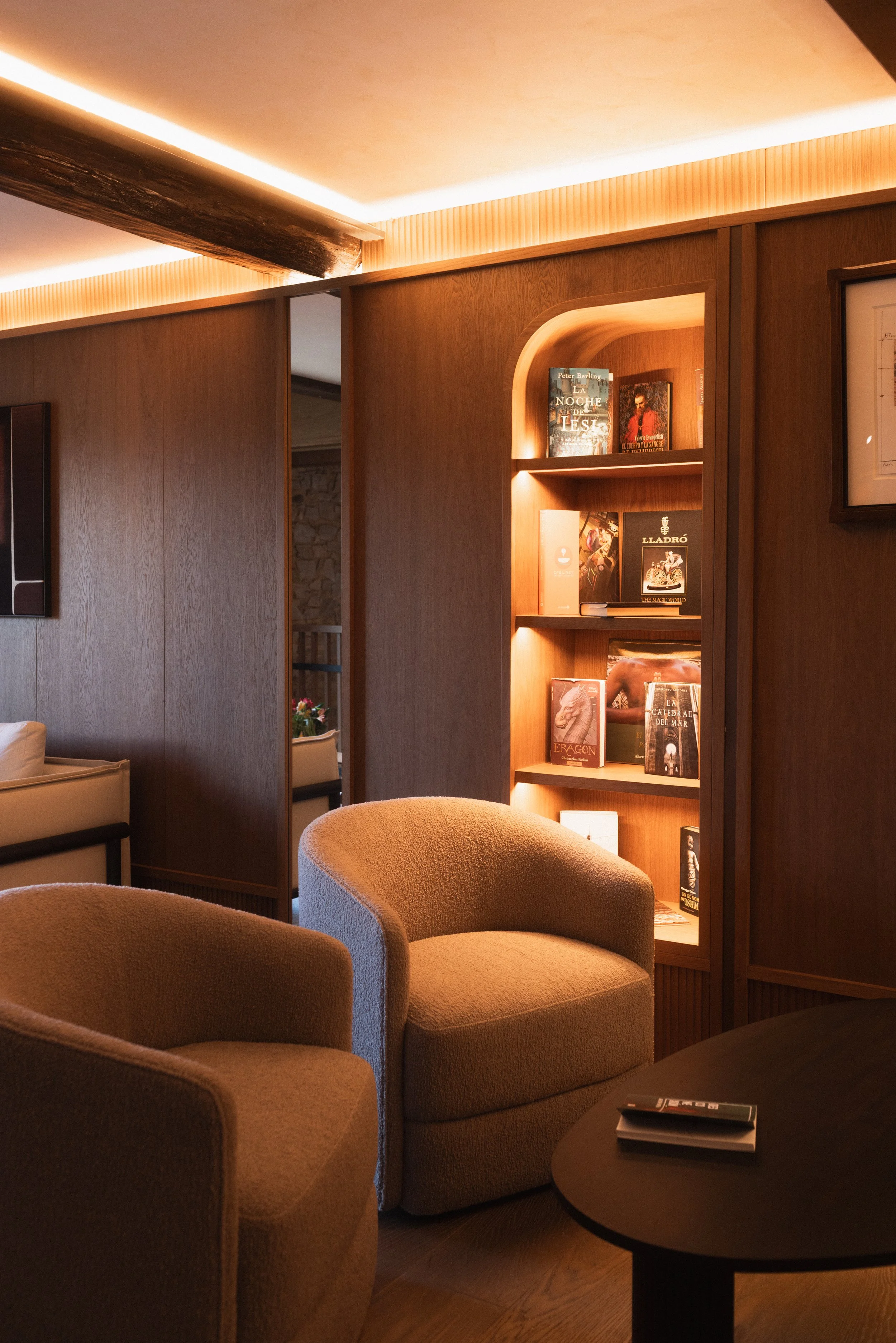 Elegant library lounge at Mas d'en Bruno luxury hotel: interior design details featuring a cozy armchair and warm lighting in Priorat.