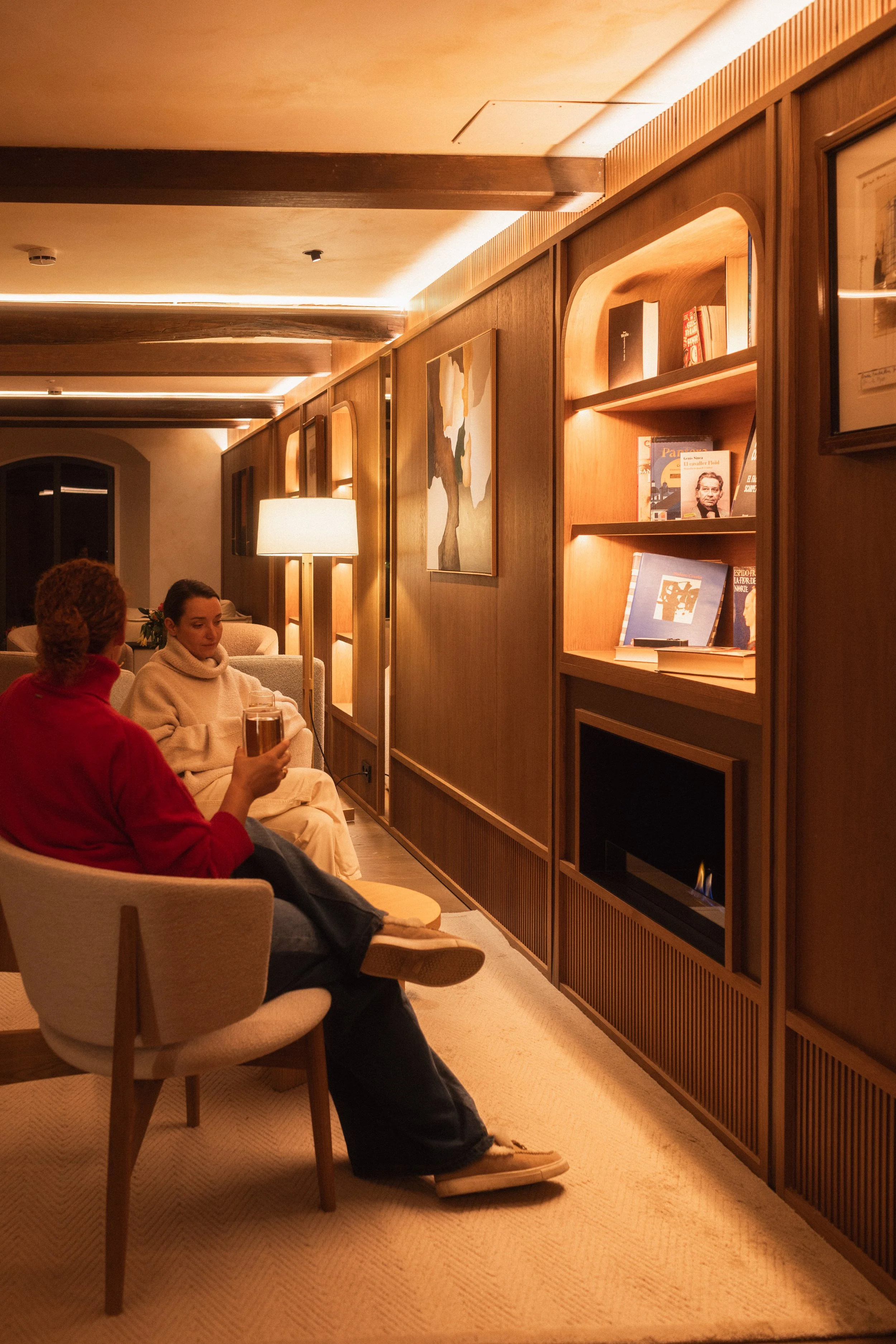 Sophisticated relaxation at Mas d'en Bruno: guests enjoying intimate conversation in the historic wood-paneled library lounge of the Priorat estate.