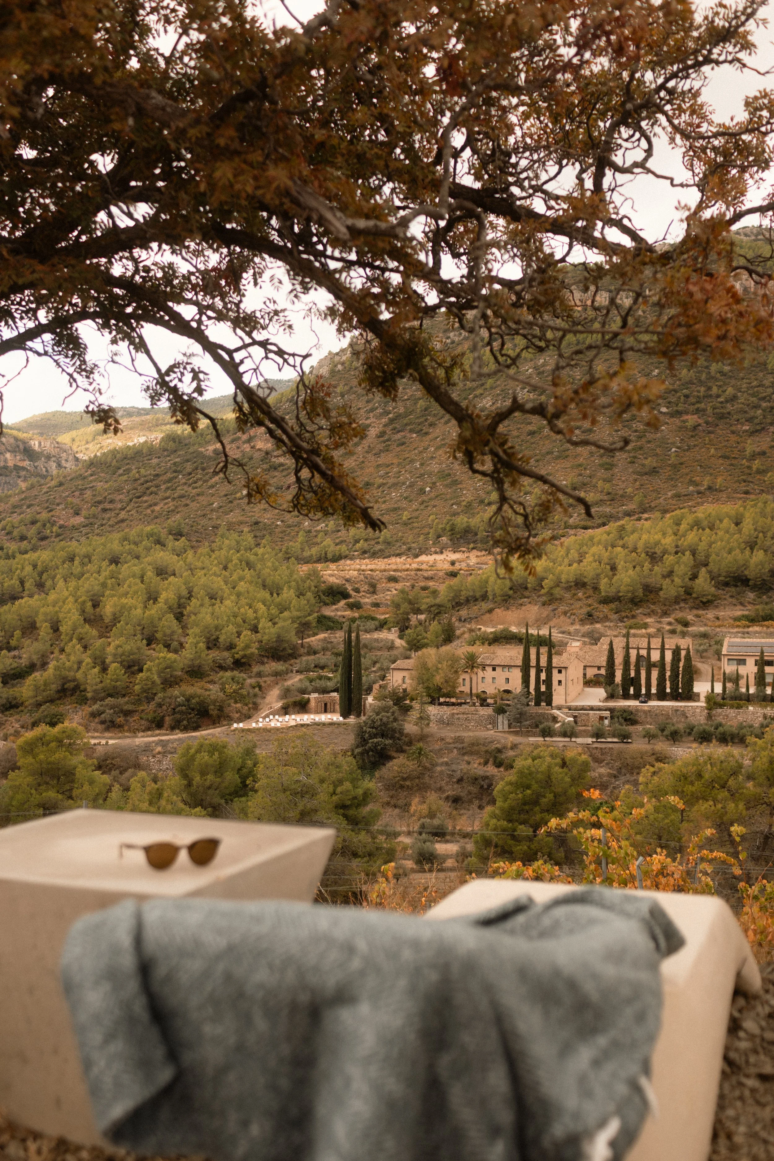 Boutique hospitality lifestyle at Terra Dominicata: sunglasses and details on a terrace overlooking the Priorat hills.