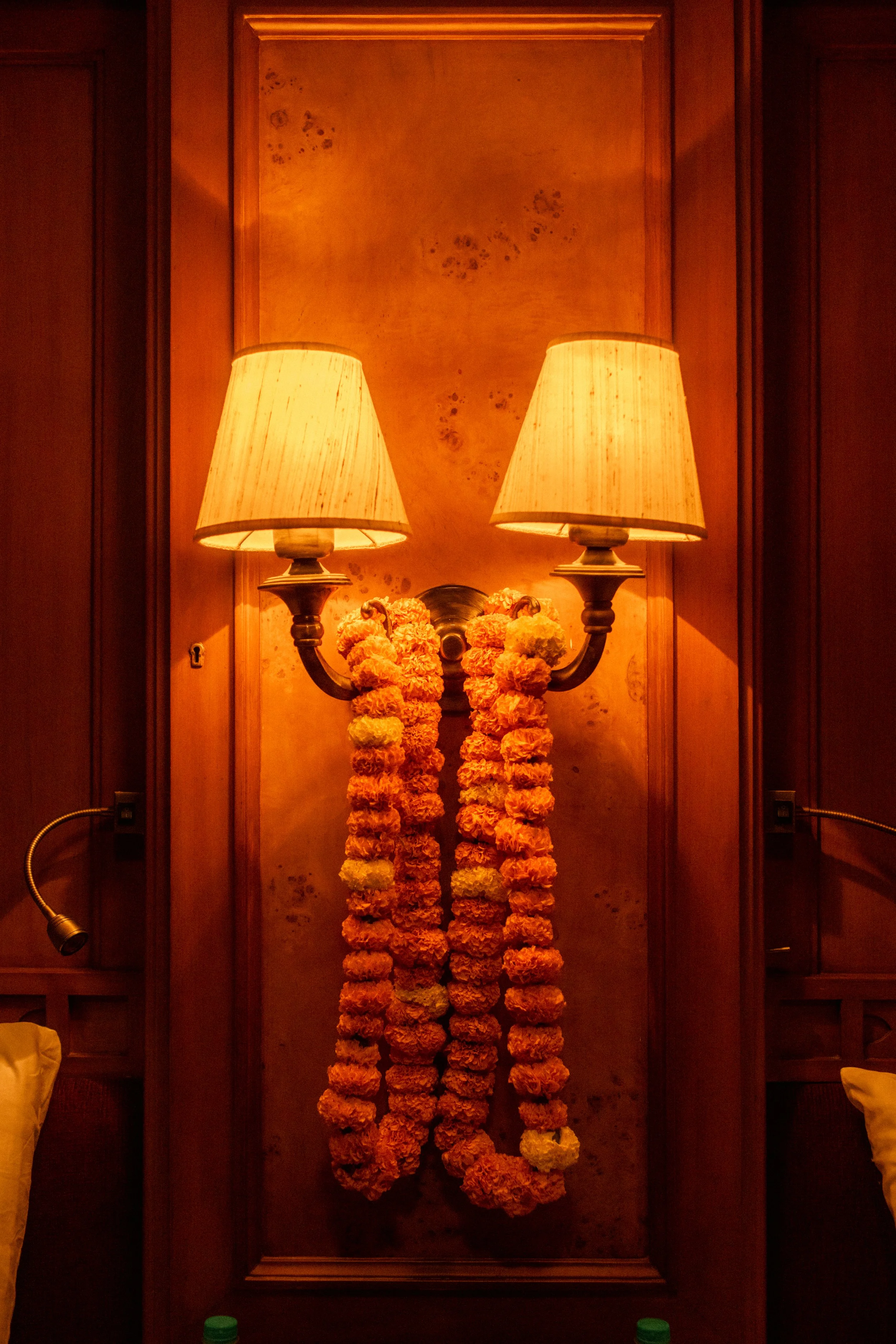 Luxury train cabin interior photography: Close-up of wall-mounted lighting decorated with traditional marigold garlands. Detail shot for Deccan Odyssey hospitality portfolio.