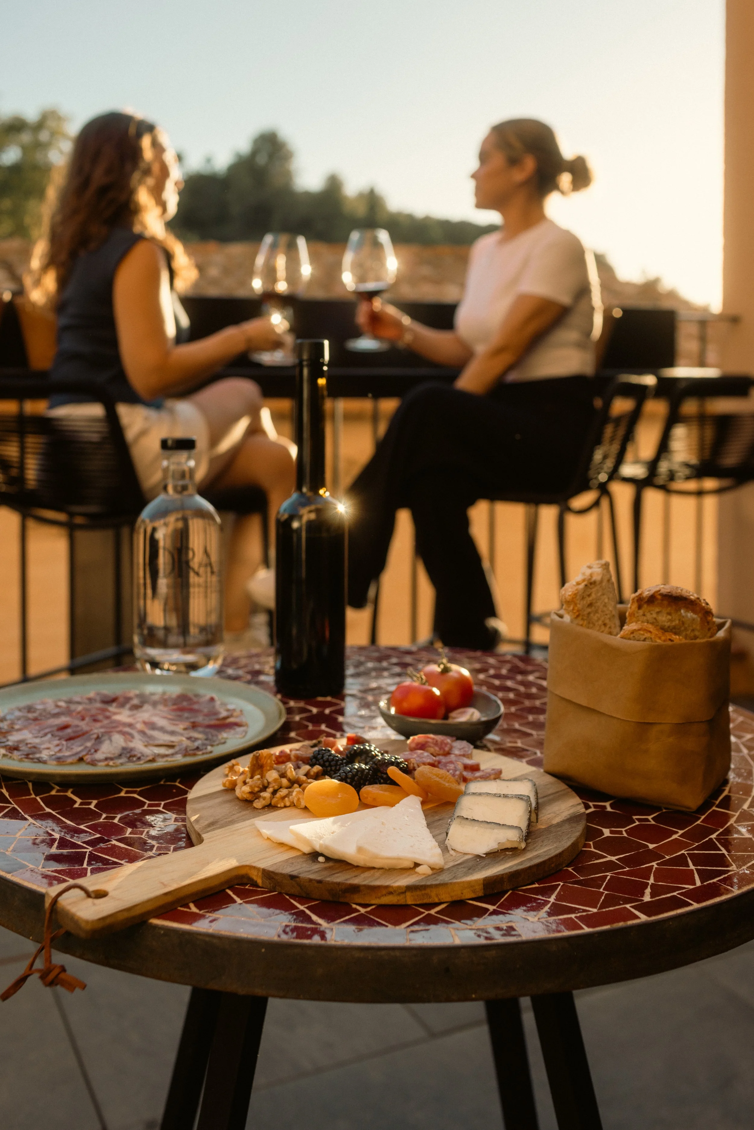 Outdoor aperitif at Ora Priorat with cheese and charcuterie board, fresh fruits, and artisanal bread at sunset. Luxury vineyard dining photography.