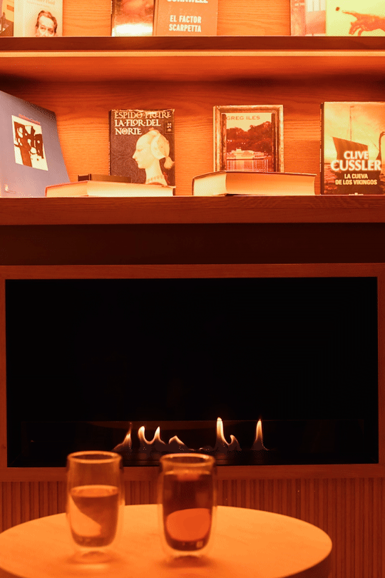 Cozy library rituals at Mas d'en Bruno: a flickering fire feature below the shelves, with steaming cups of tea ready for a relaxing evening in Priorat.