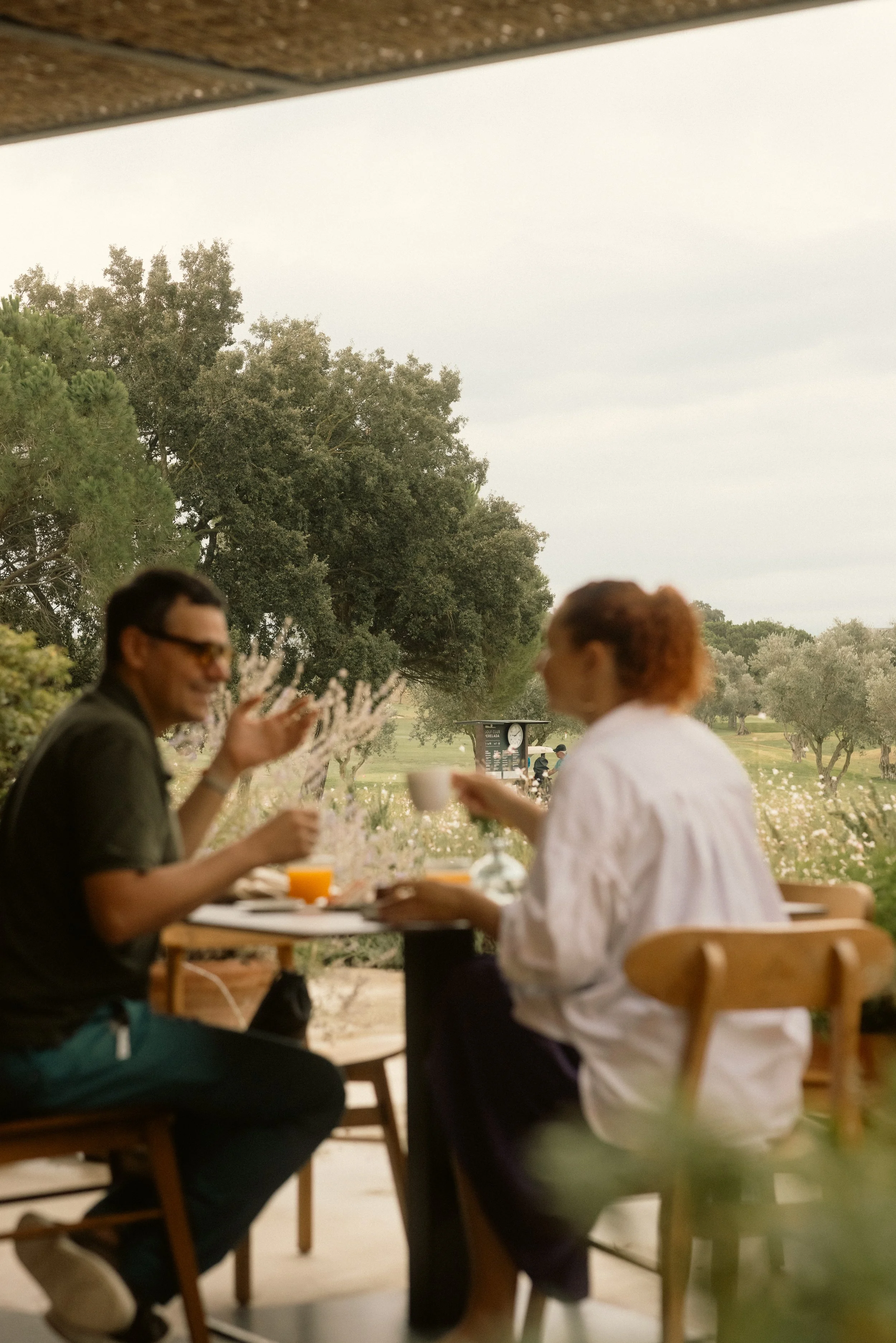 Cinematic guest lifestyle at Club de Golf Perelada: social coffee on the terrace overlooking the expansive green course.