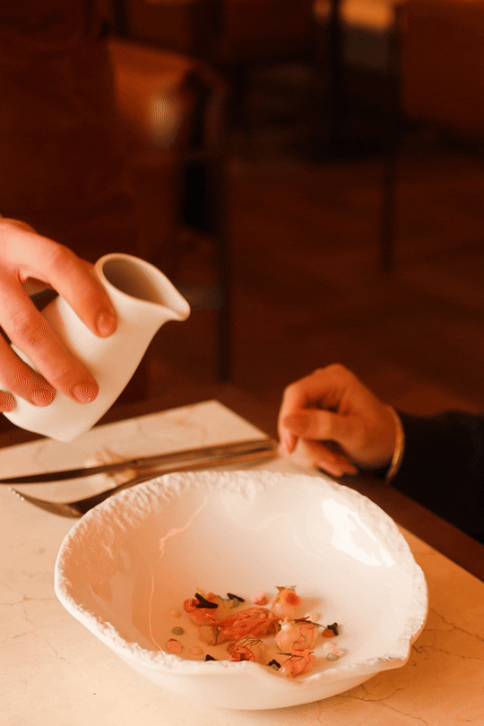 Fine dining excellence at Mas d'en Bruno: a delicate sauce being poured over a gourmet seafood dish at the hotel's premier Priorat restaurant.