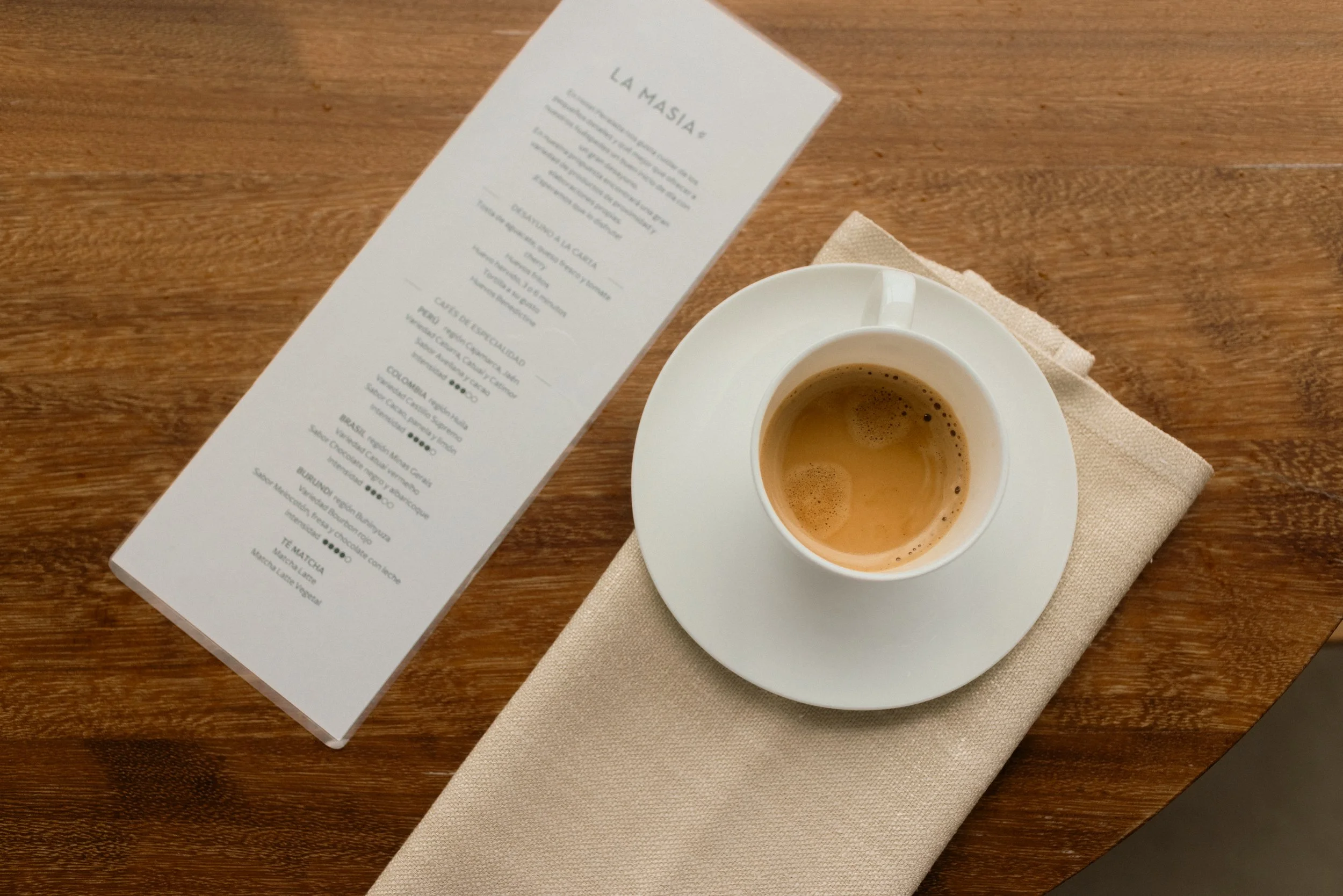 Gourmet coffee ritual at Hotel Perelada: artisanal espresso on a wooden table with a curated menu in a luxury resort setting.