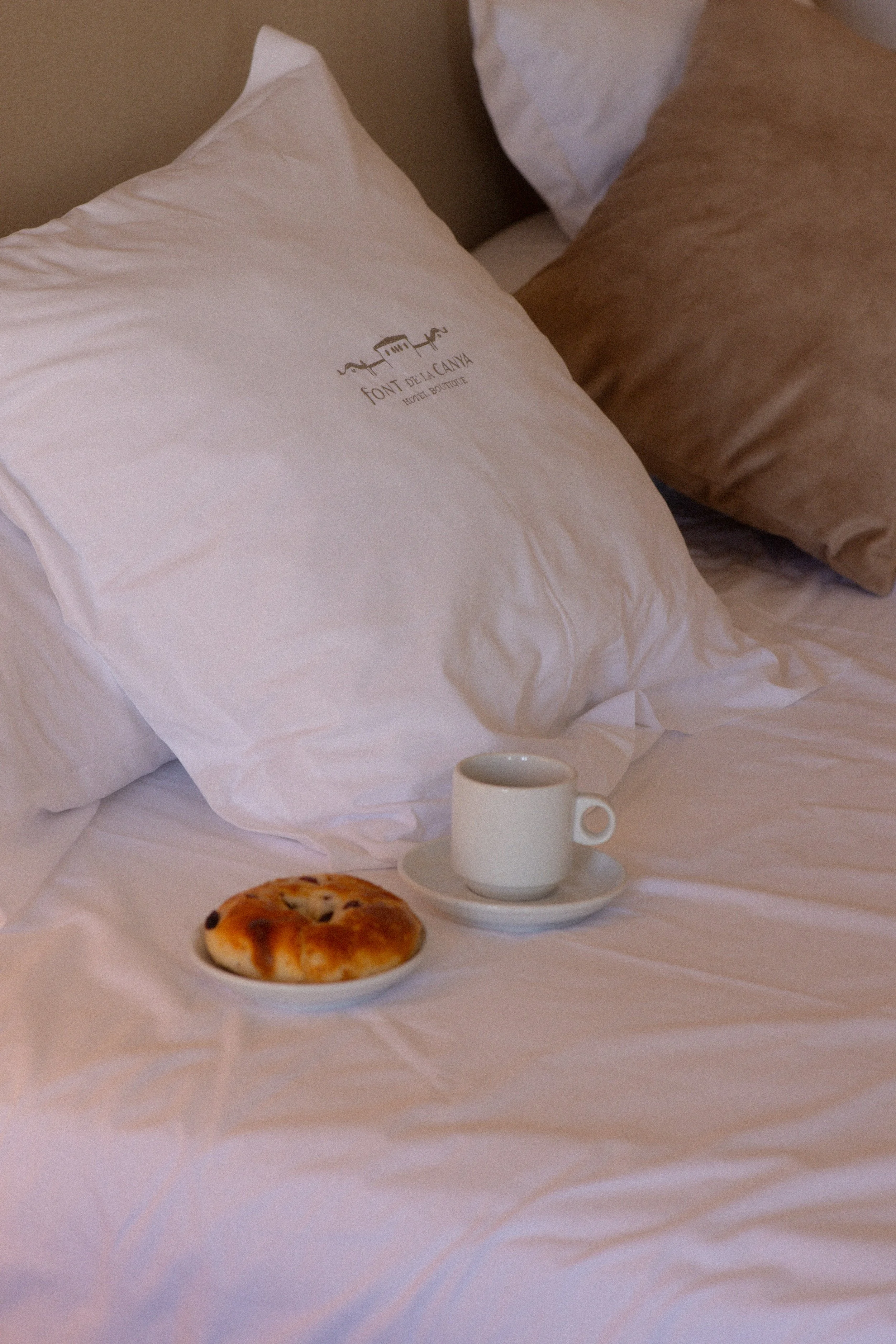 Luxury breakfast in bed at Font de la Canya Boutique Hotel: coffee and pastry on signature embroidered linens.