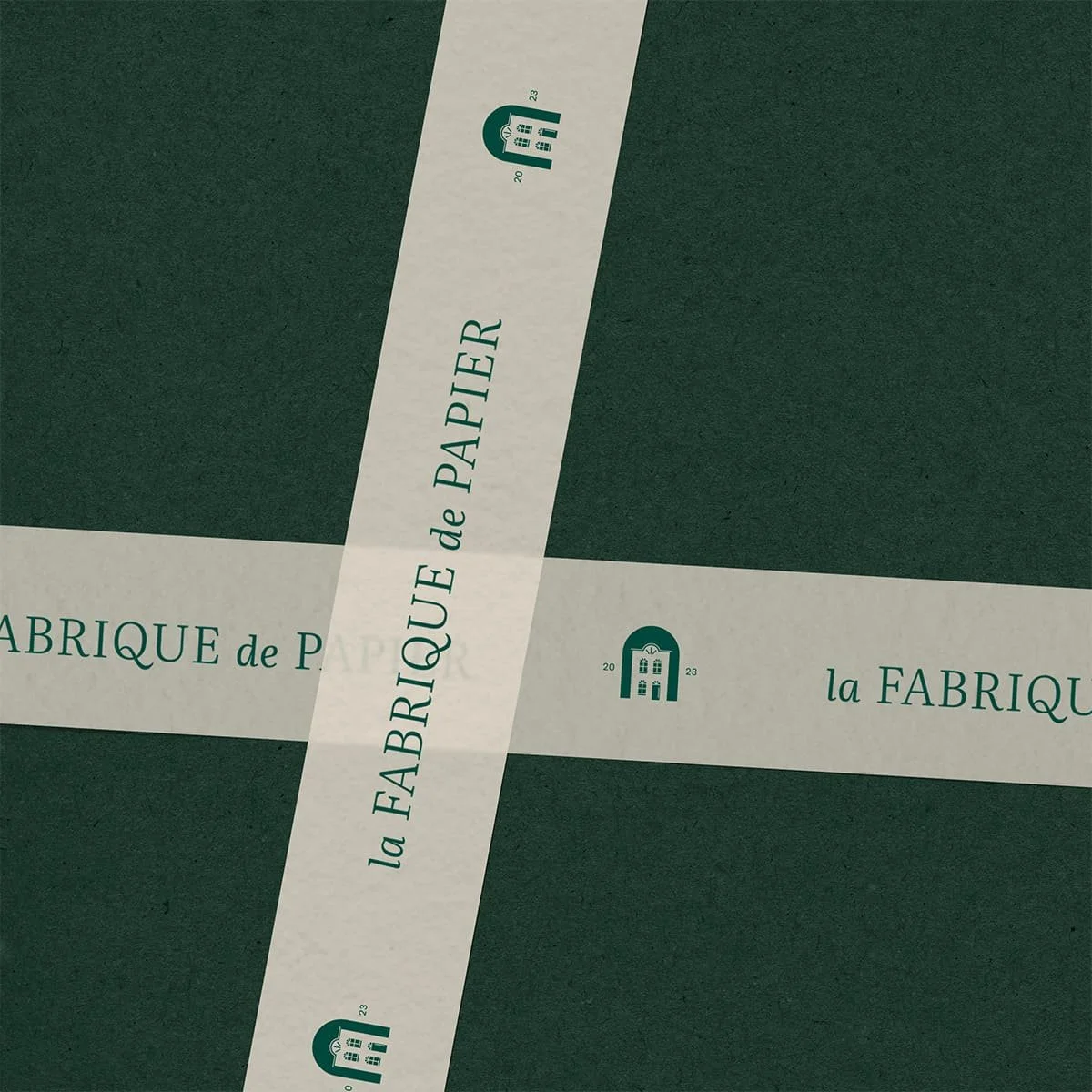Mise en situation de l'identité de marque de La Fabrique de Papier sur un emballage vert foncé.