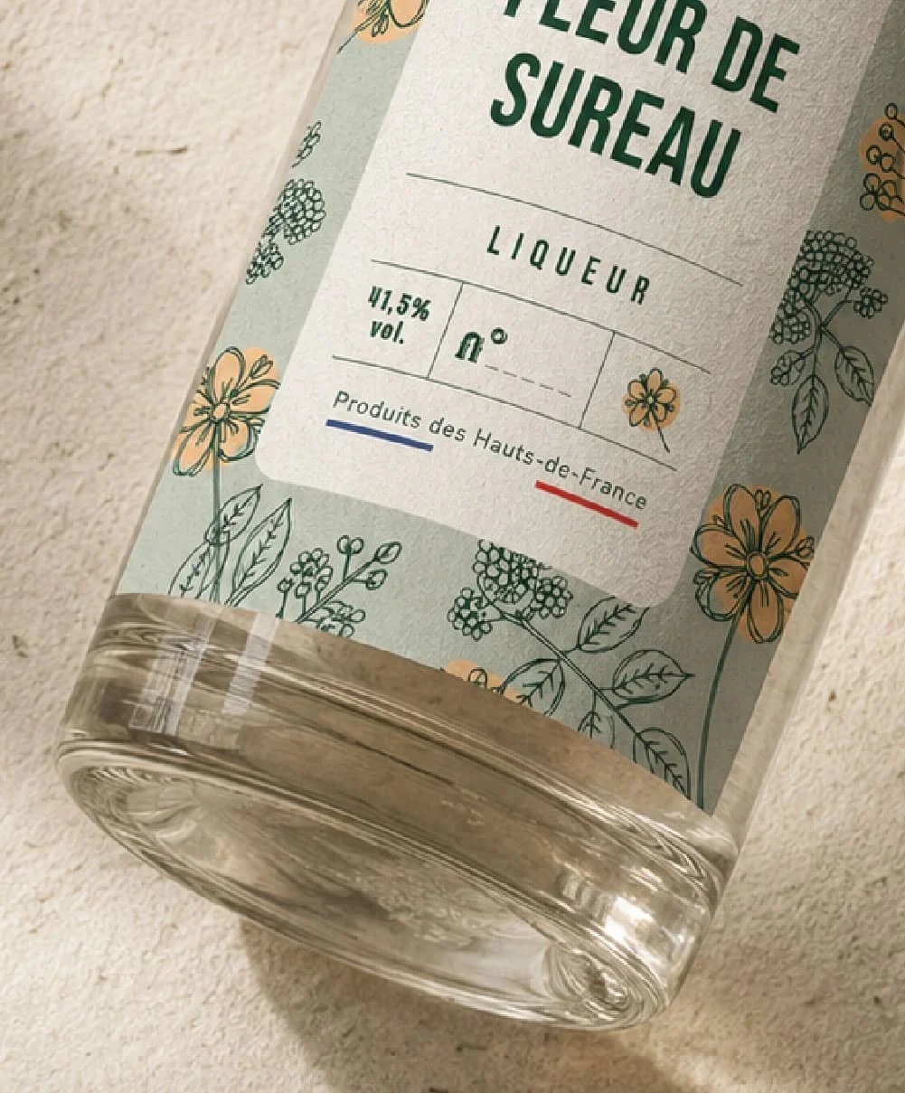 Focus sur un packaging de Gueules Noires, distillerie artisanale et spiritueux, Hauts-de-France. Packaging premium, motifs floraux et élégants.