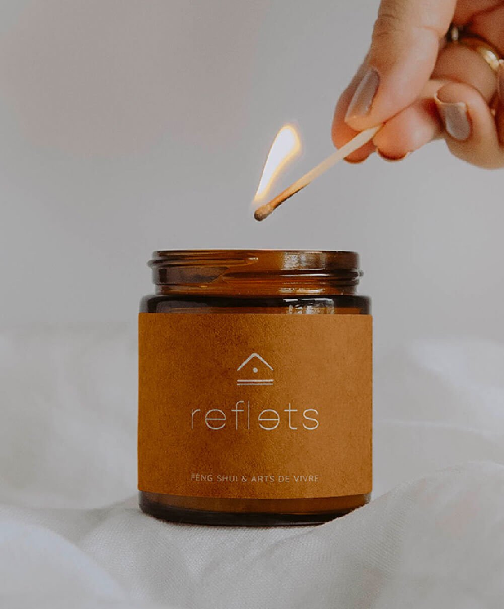 Mise en situation du logo de Reflets feng shui sur le packaging, l'étiquette ocre d'une bougie.