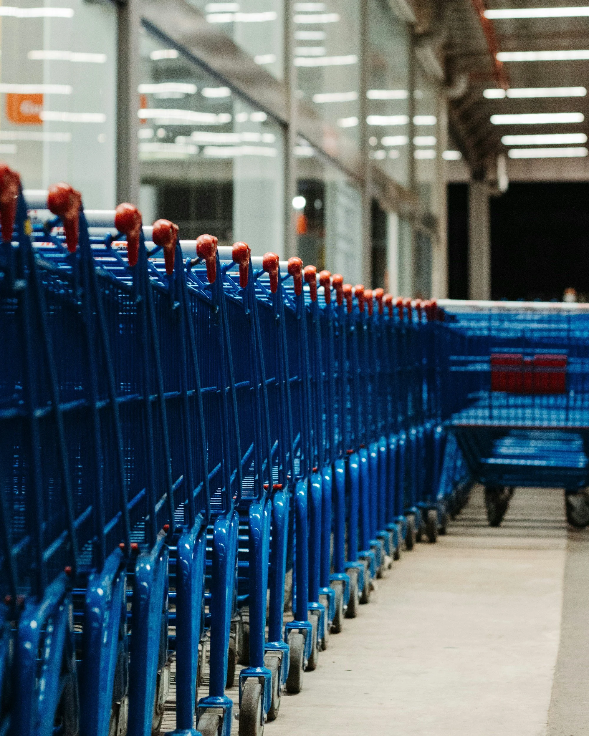 Ligne de chariots bleus vides dans un couloir d'un supermarché.