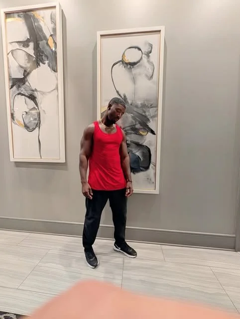 A person standing in front of abstract black, white, gray, and yellow artwork in an art gallery.