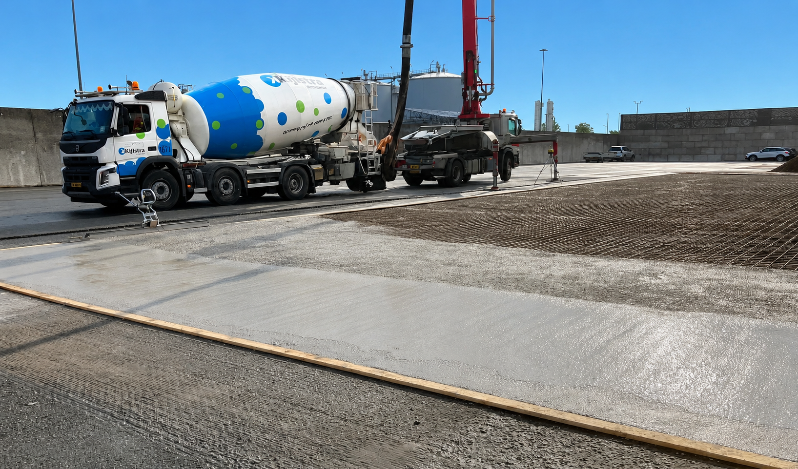 Een betonmixer wordt afgevuld met beton door een grote betonpomp op een bouwplaats.