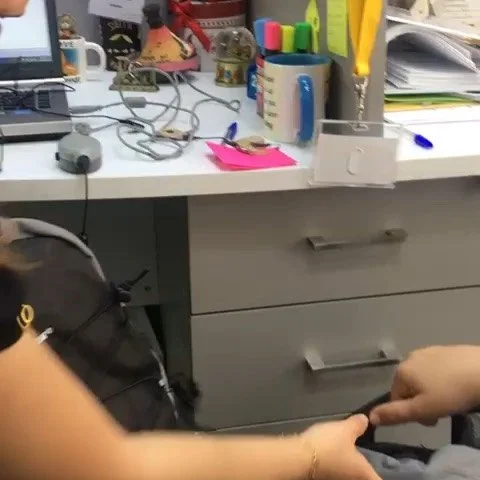 Office desk with various stationery, a computer, and a hand holding another hand.