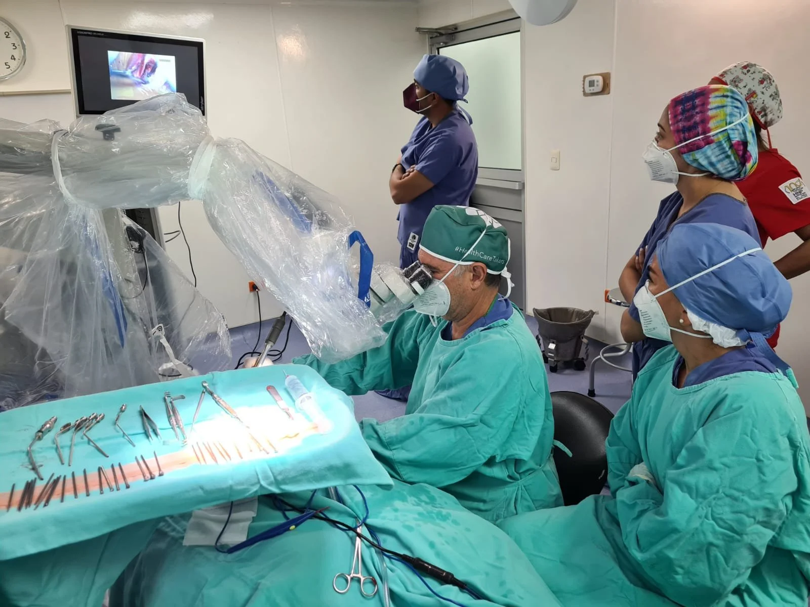 Medical team performing surgery using advanced surgical tools and a microscope in an operating room.