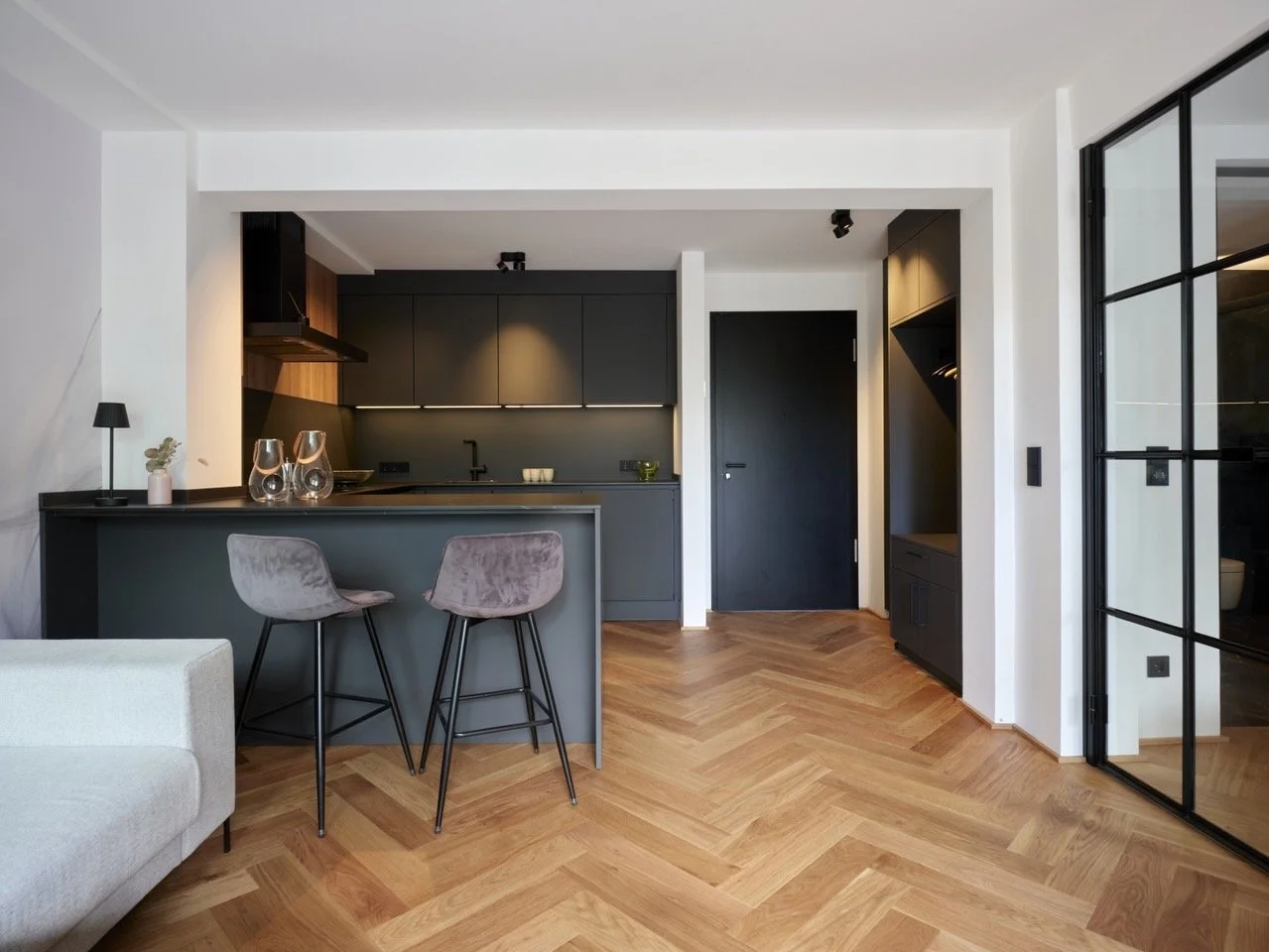 Moderner Küchenbereich mit dunklen Schränken, Holzfußboden und Sitzecke mit zwei Stühlen in der Ferienwohnung in Bremen-Schwachhausen.