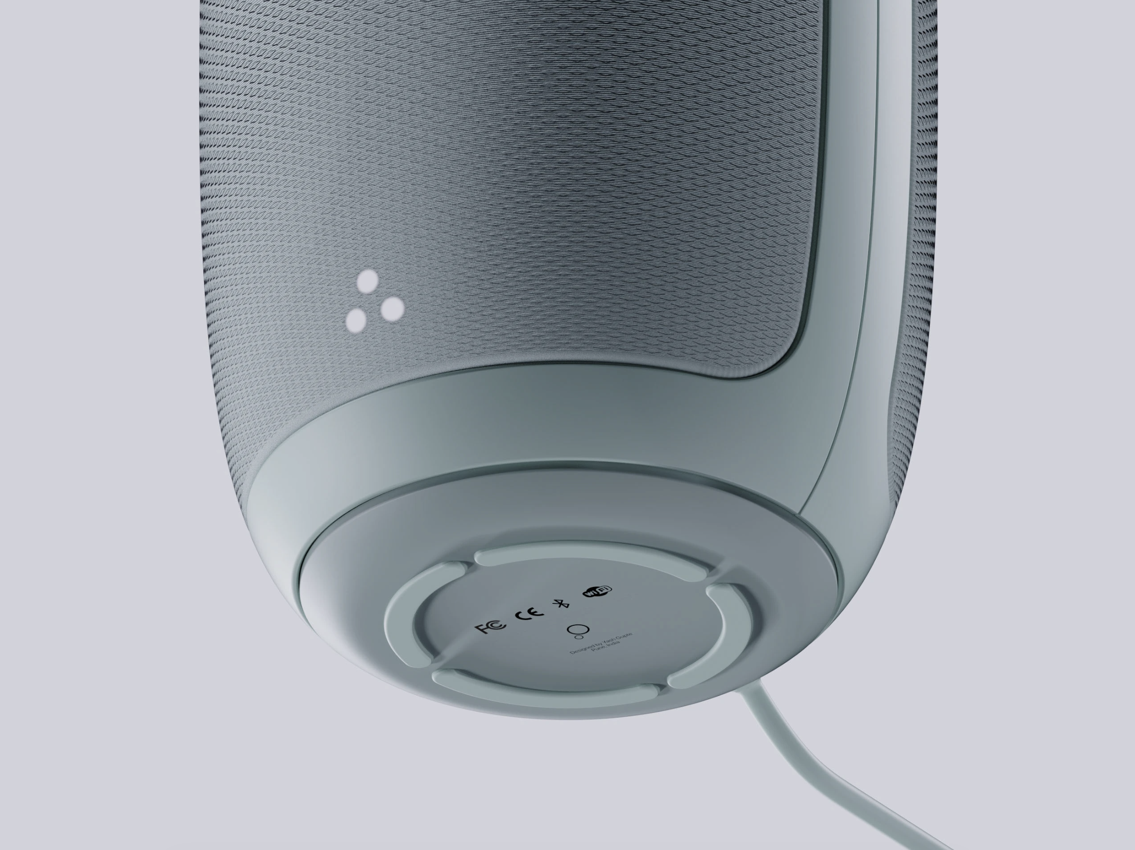 Close-up of the bottom of a modern white smart speaker with a circular base, some certification markings, and a visible power cord.