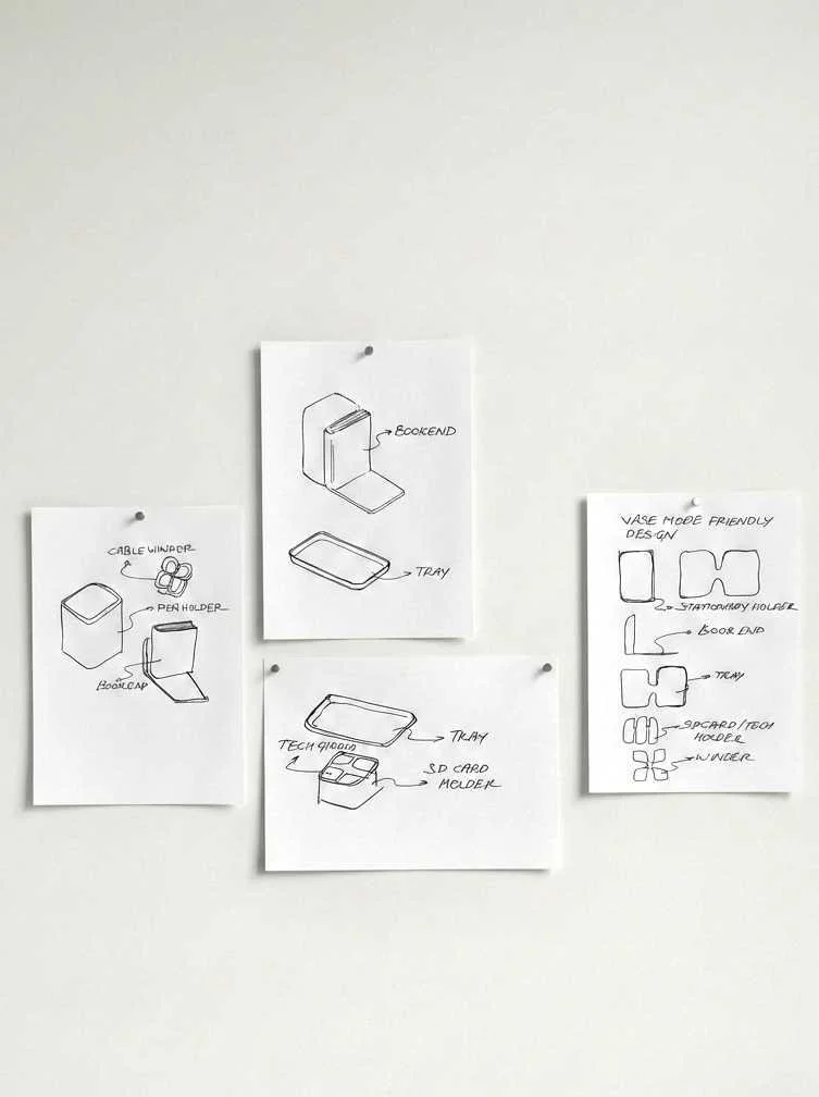 Three sketches of tech gadgets and accessories, including a cable winder with pen holder, a bookend with a tray, and a device with a tray, SD card slot, and 3D card model.