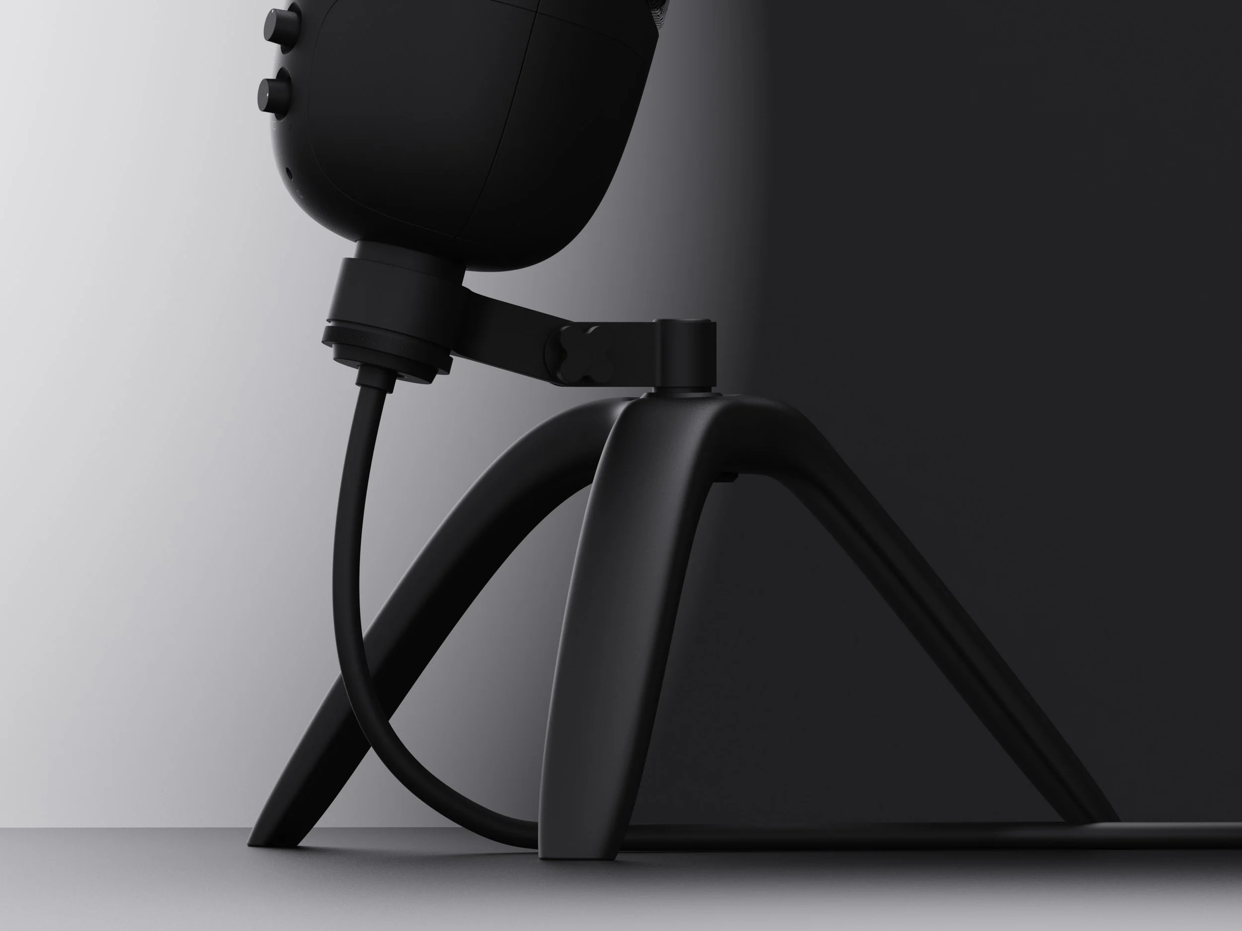 Close-up of a black electronic device, possibly a speaker or camera, connected to a stand or tripod against a gray background.