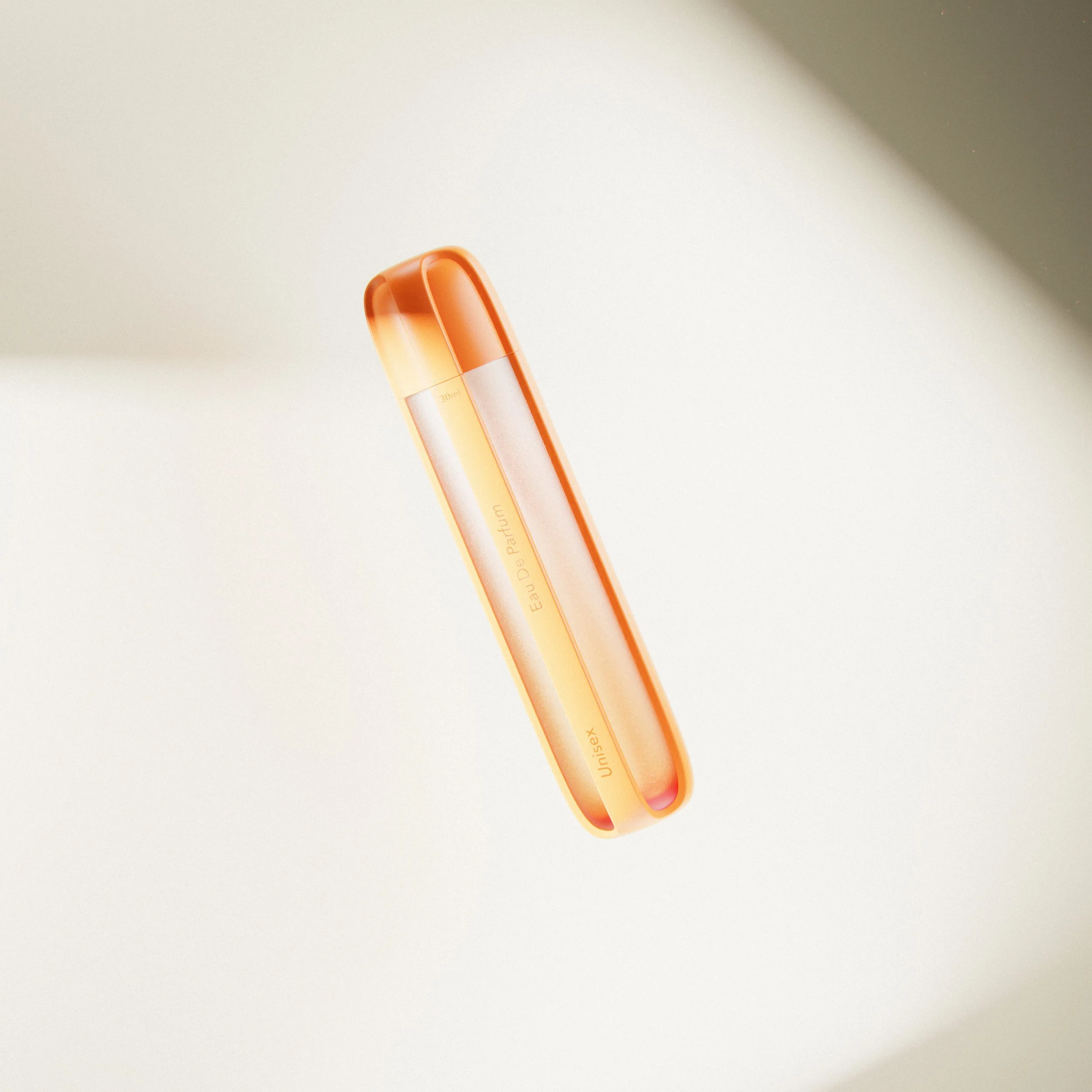 Orange and white perfume bottle with the label 'Eau De Parfum, Unisex' on a beige surface.