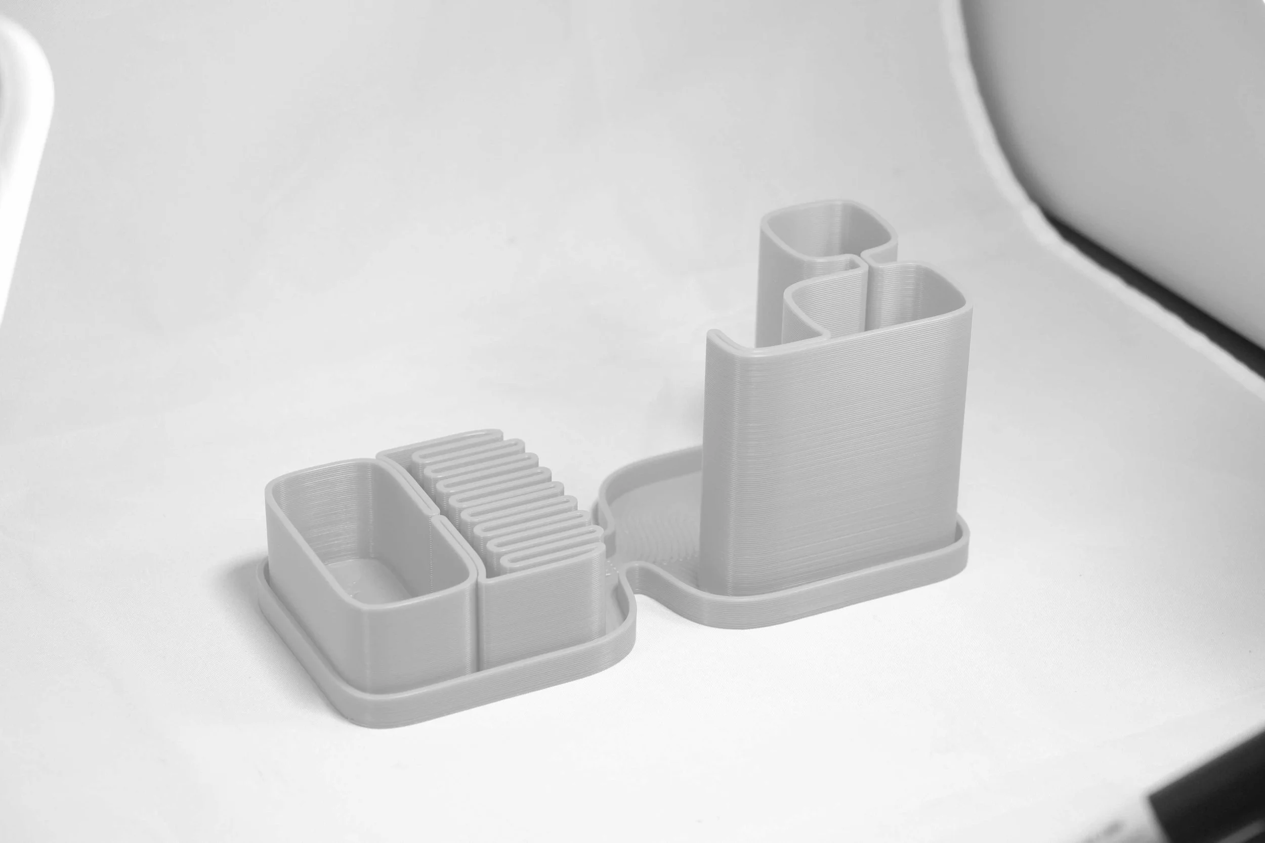 A white multi-compartment desk organizer on a white surface with small compartments for organizing office supplies.