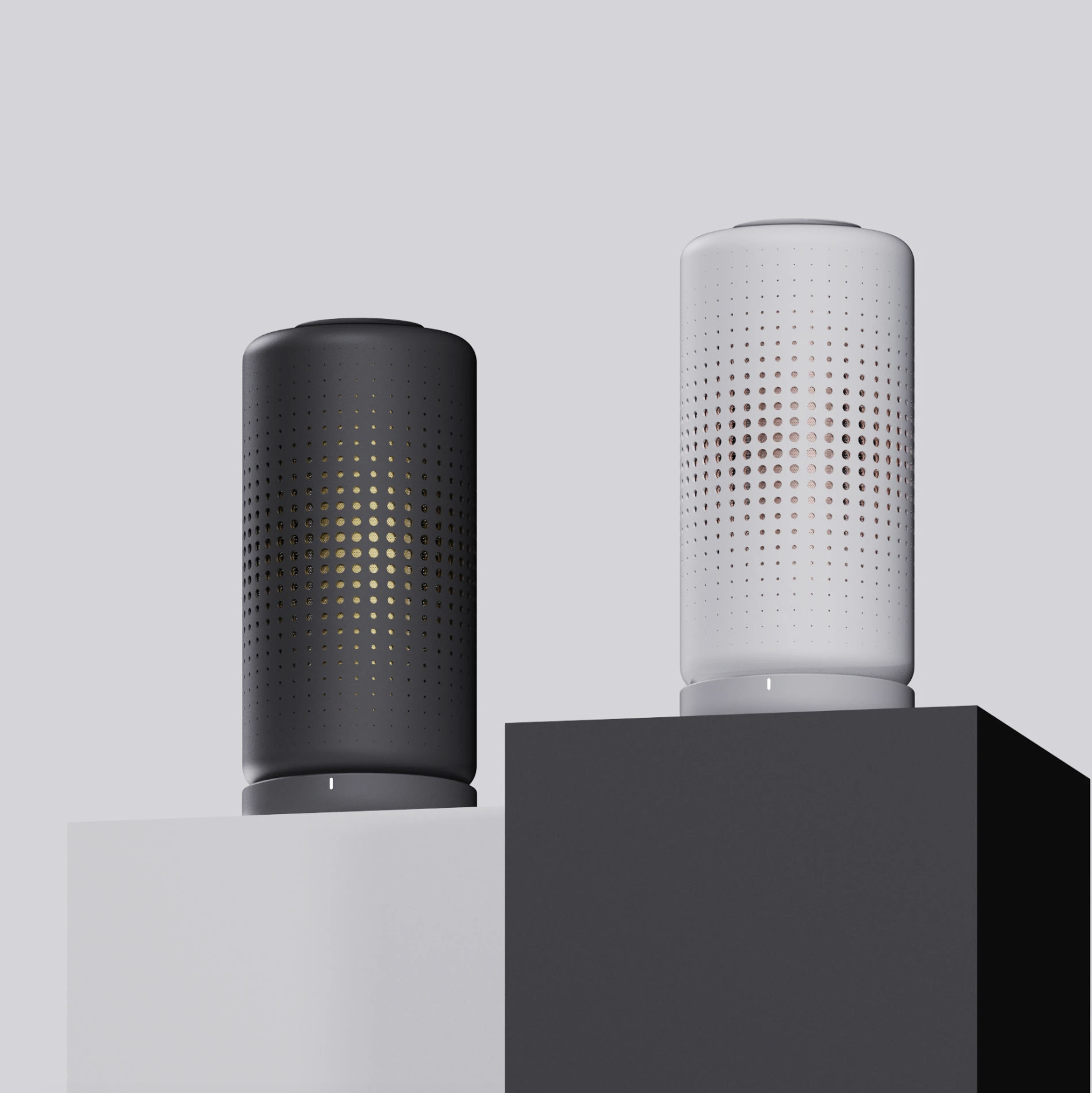 Two cylindrical smart speakers, one black with gold accents on the left and one white with gold accents on the right, placed on contrasting white and black pedestals against a light gray background.