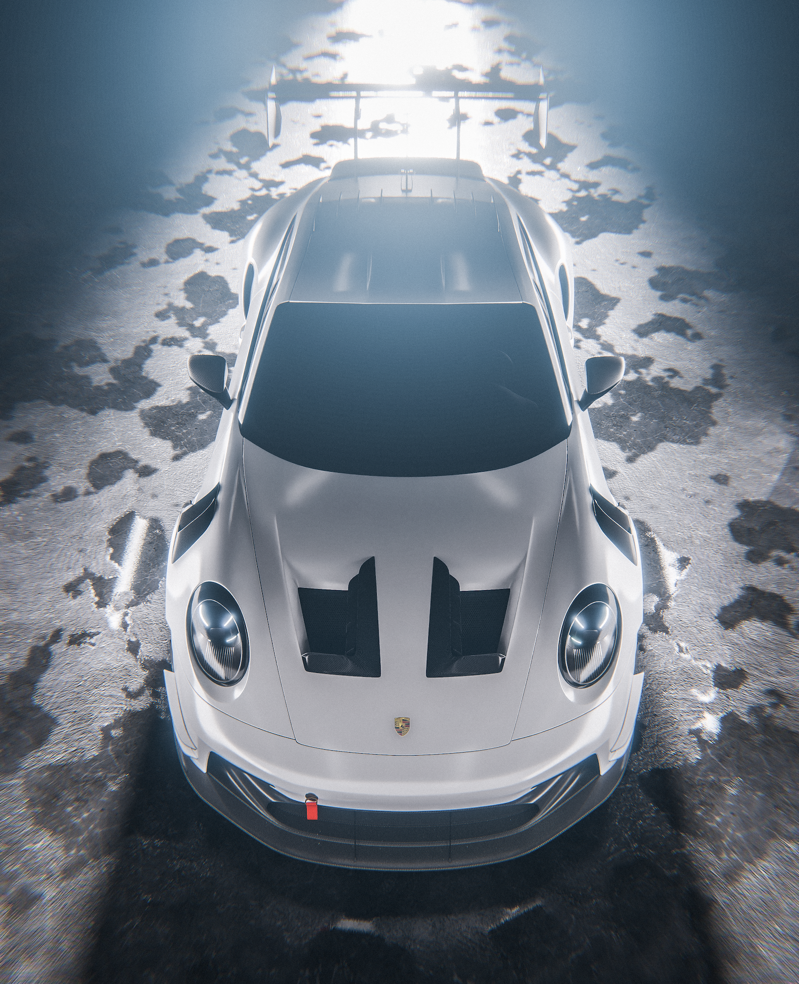 Top view of a silver Porsche race car on a textured surface with patches of snow.